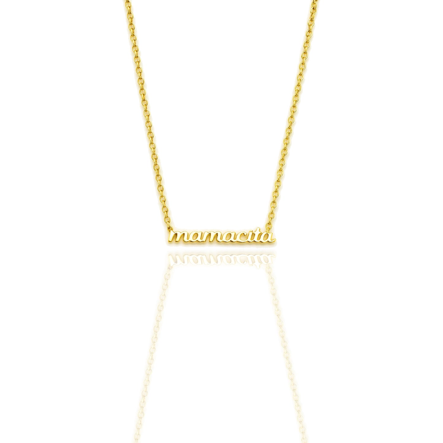 Close-up of an 18K gold filled necklace with “mamacita” in polished script font on a dainty cable chain, shown on a white reflective background.