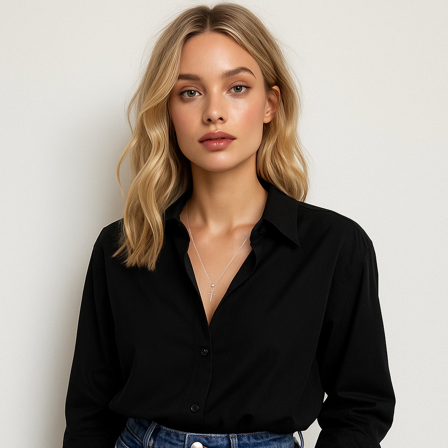 Minimalist sterling silver cross pendant necklace for her, layered elegantly with casual black button-down shirt and soft waves.