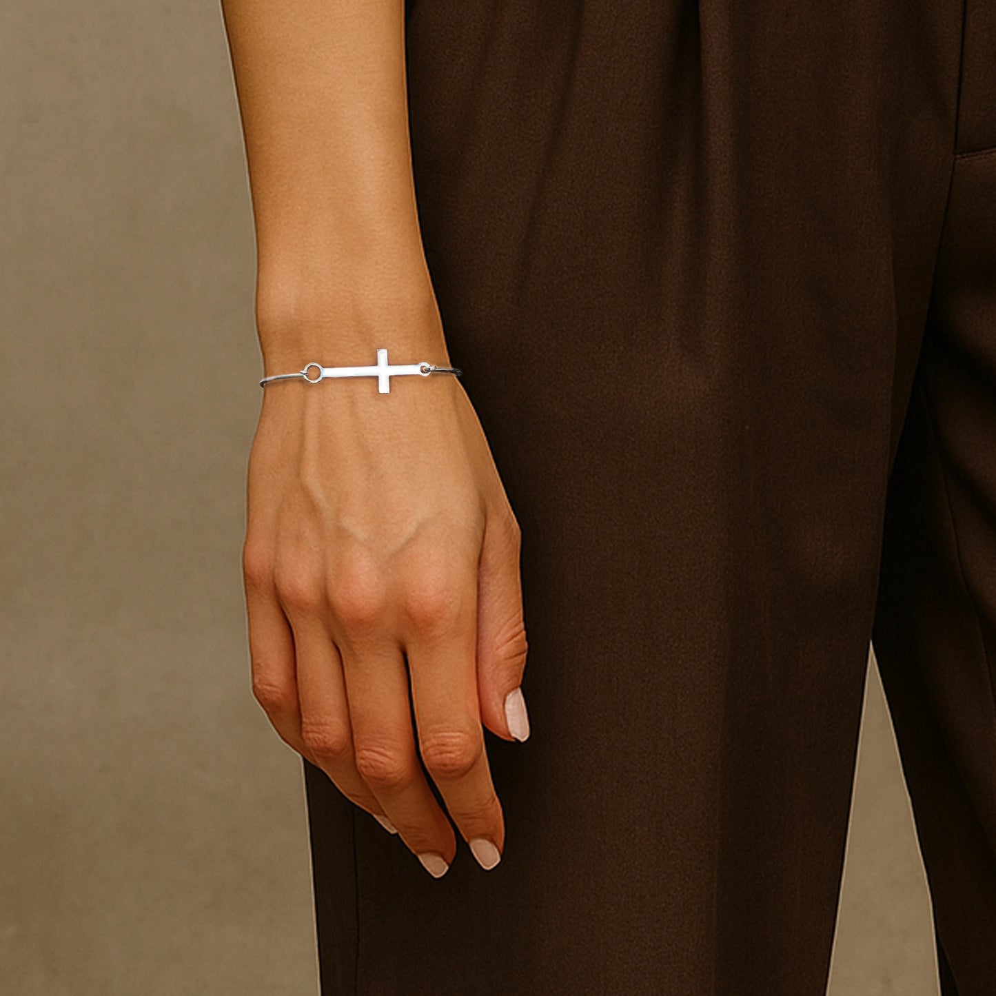 Minimalist sterling silver cuff bracelet with a sleek horizontal cross design, worn by a woman in a brown outfit with a relaxed hand pose.