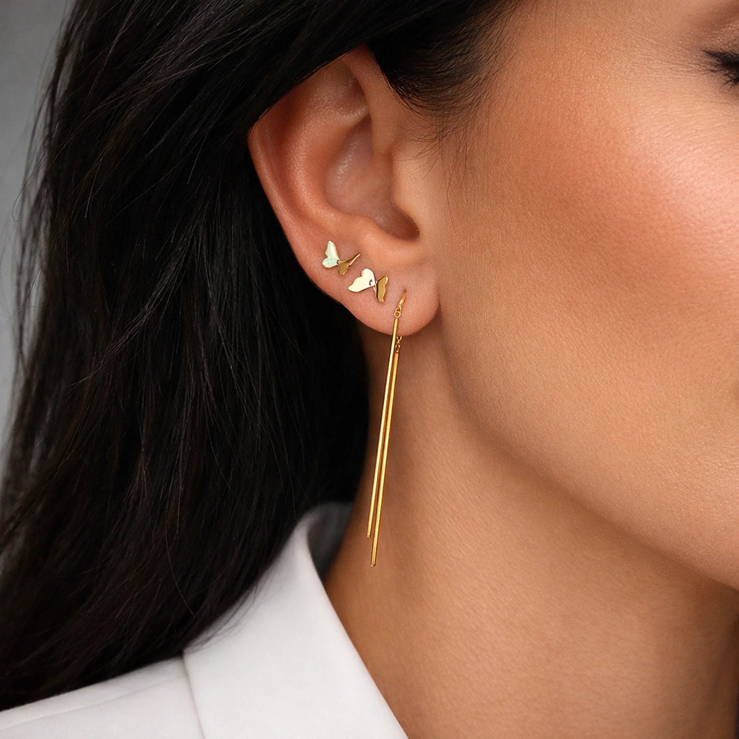 Long gold threader earrings with butterfly studs on model, minimalist gold earrings close-up jewelry photo