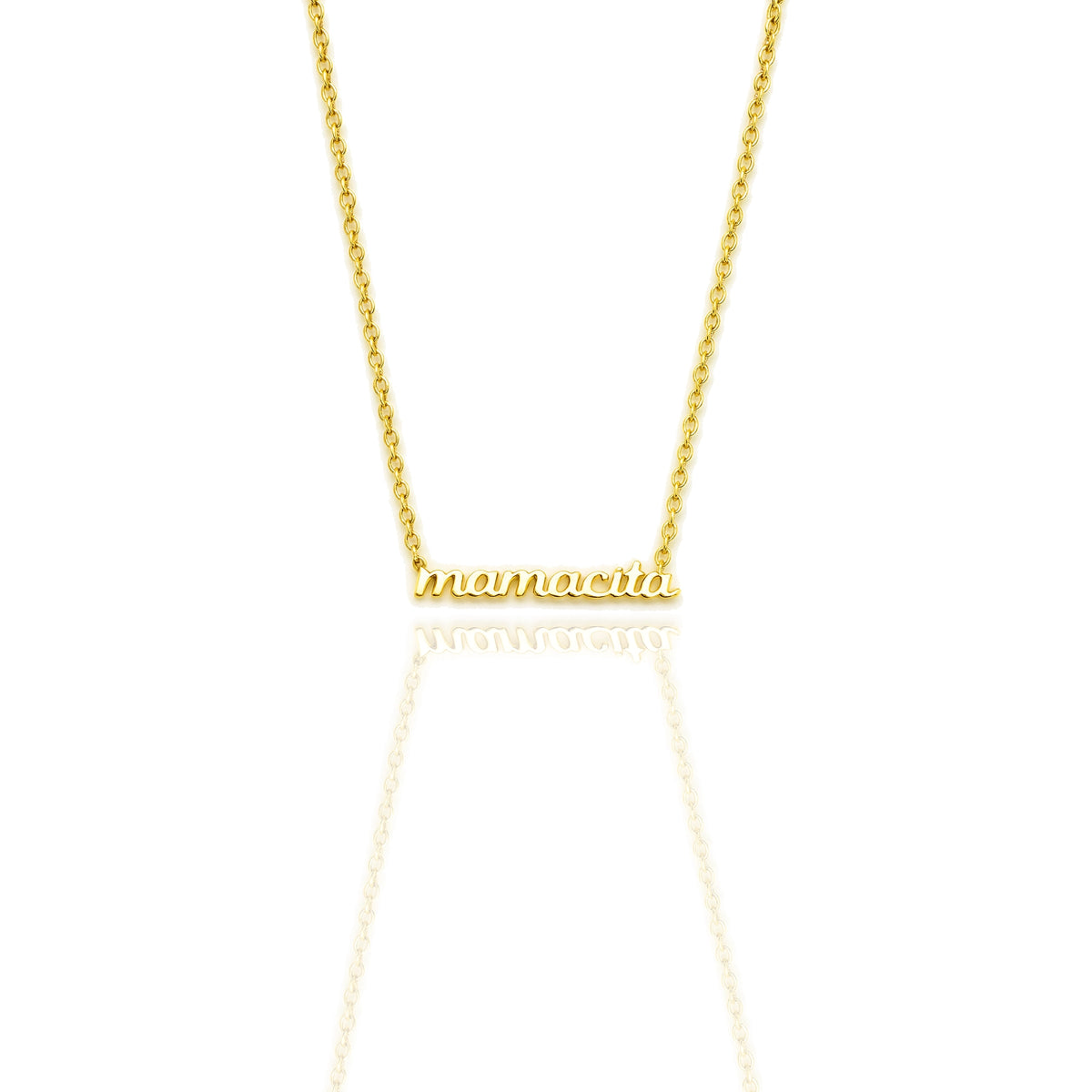 Close-up of an 18K gold filled necklace with “mamacita” in polished script font on a dainty cable chain, shown on a white reflective background.