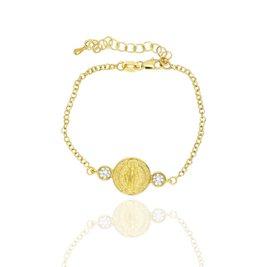 18K gold filled Saint Benedict medallion bracelet featuring a round religious charm centered between two sparkling cubic zirconia stones on a delicate adjustable chain, displayed on a white reflective background.