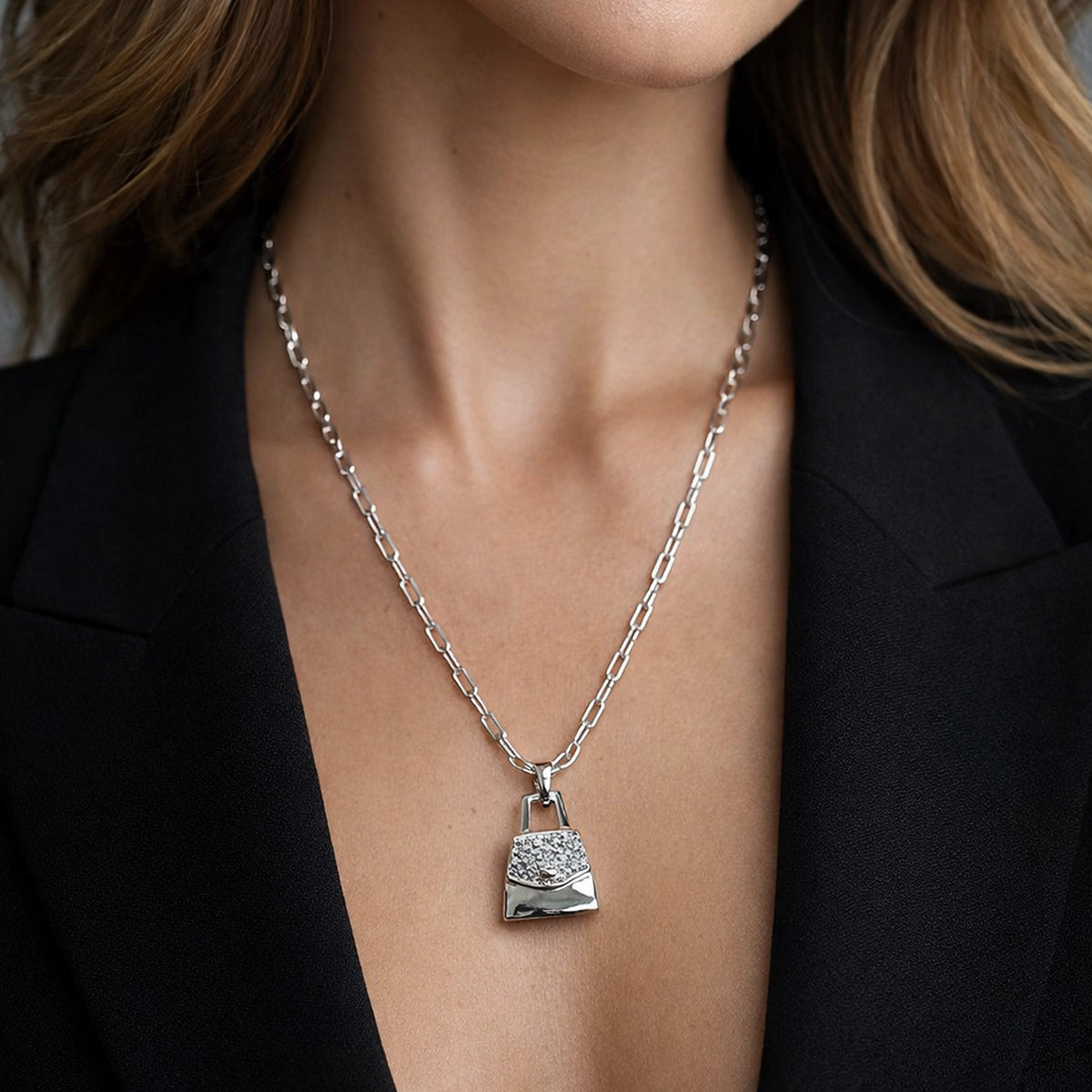 Rectangular paperclip chain necklace with purse pendant featuring CZ stones, silver tone, worn on model neck, minimalist elegant jewelry, close-up with professional studio lighting
