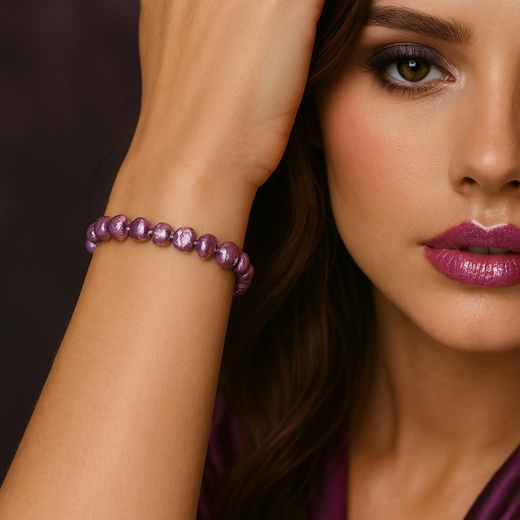 Close-up of model’s wrist wearing an elastic lilac baroque freshwater pearl bracelet - small irregular pearls - one smoky eye visible, glossy purple lips.
