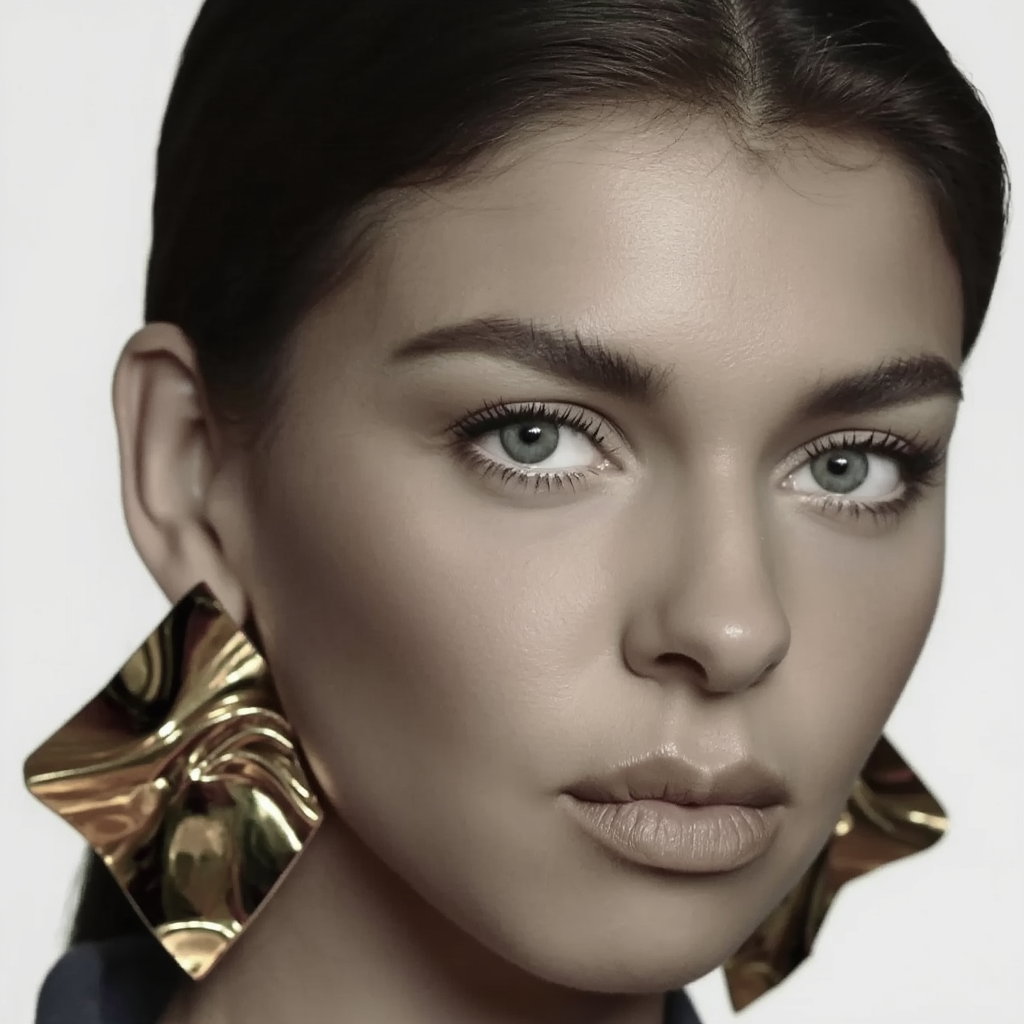 Close-up of a woman wearing large gold earrings with a neutral background