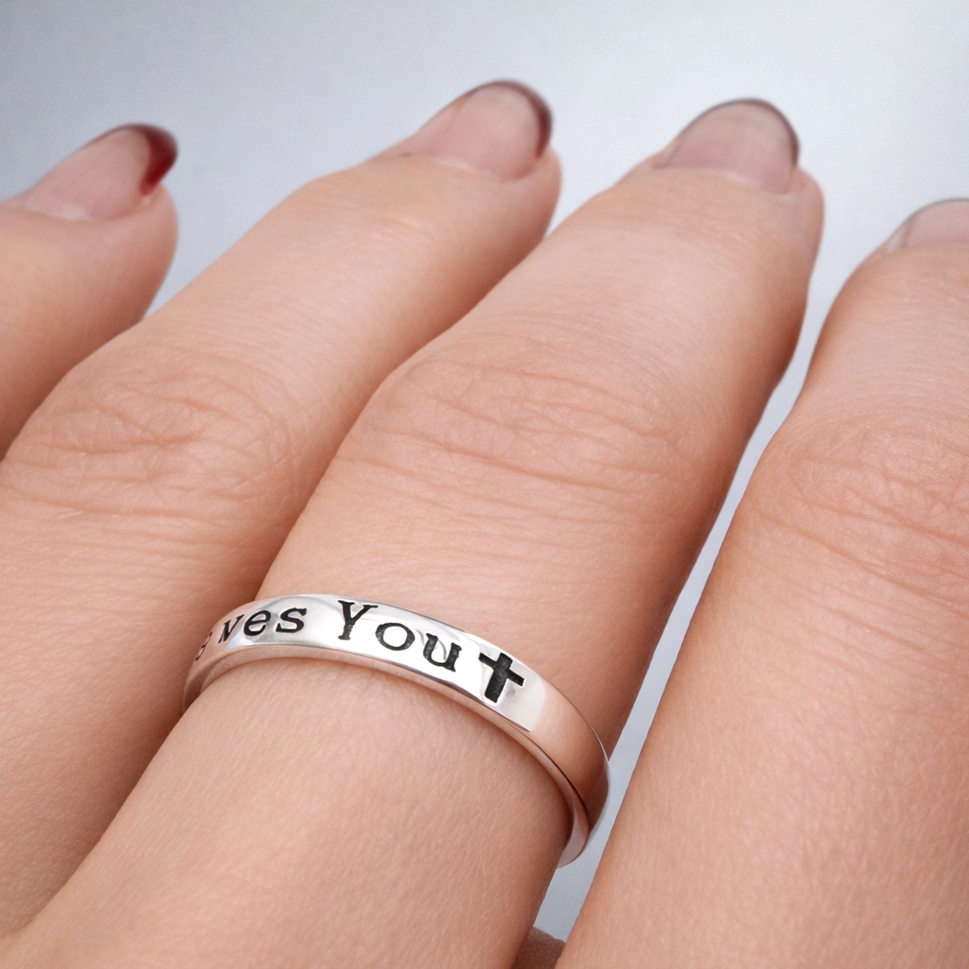 Minimalist Christian band ring engraved “Jesus Loves You” with cross icon, polished silver religious ring worn on hand