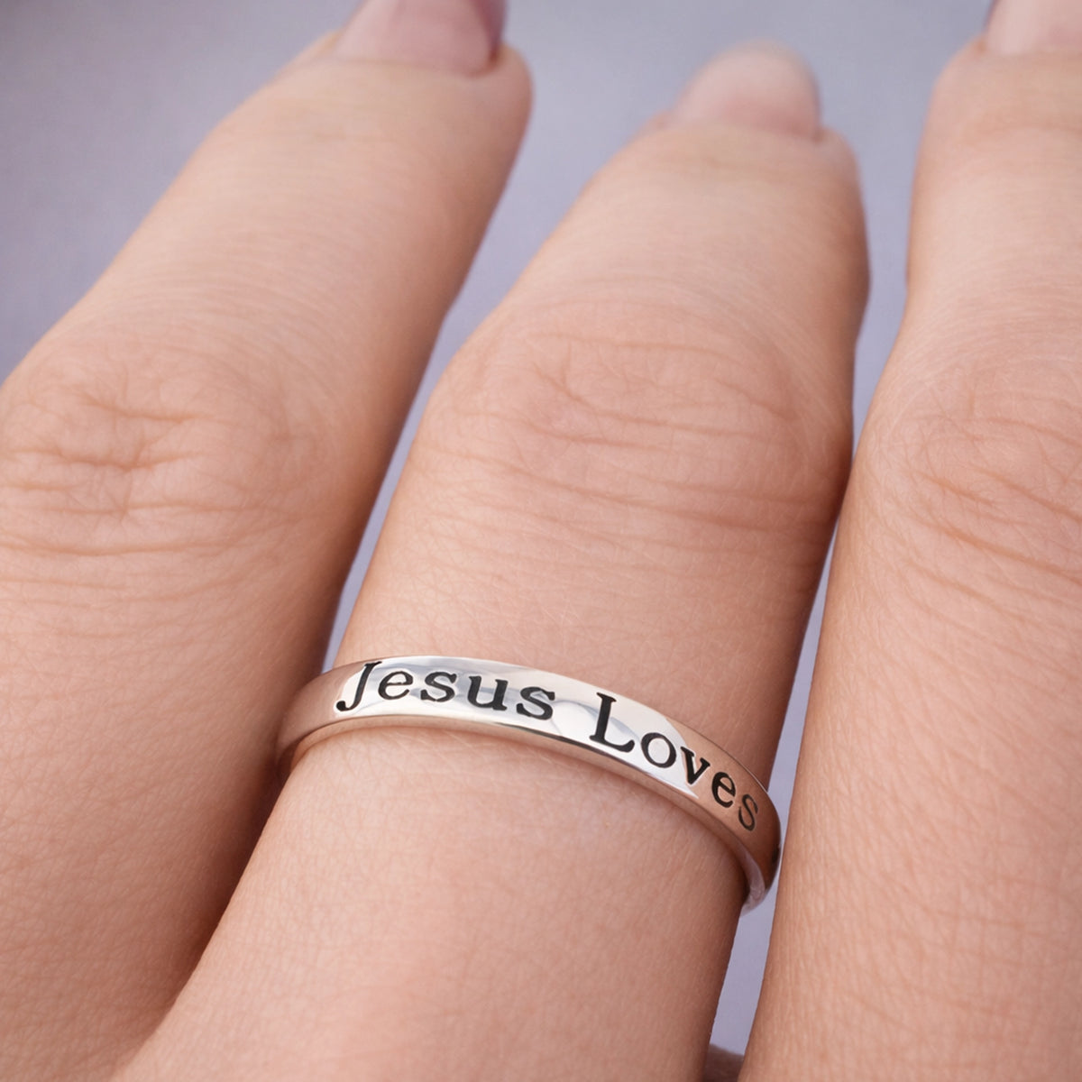 Sterling silver engraved Christian band ring with “Jesus Loves You” inscription and cross symbol, minimalist faith jewelry worn on finger