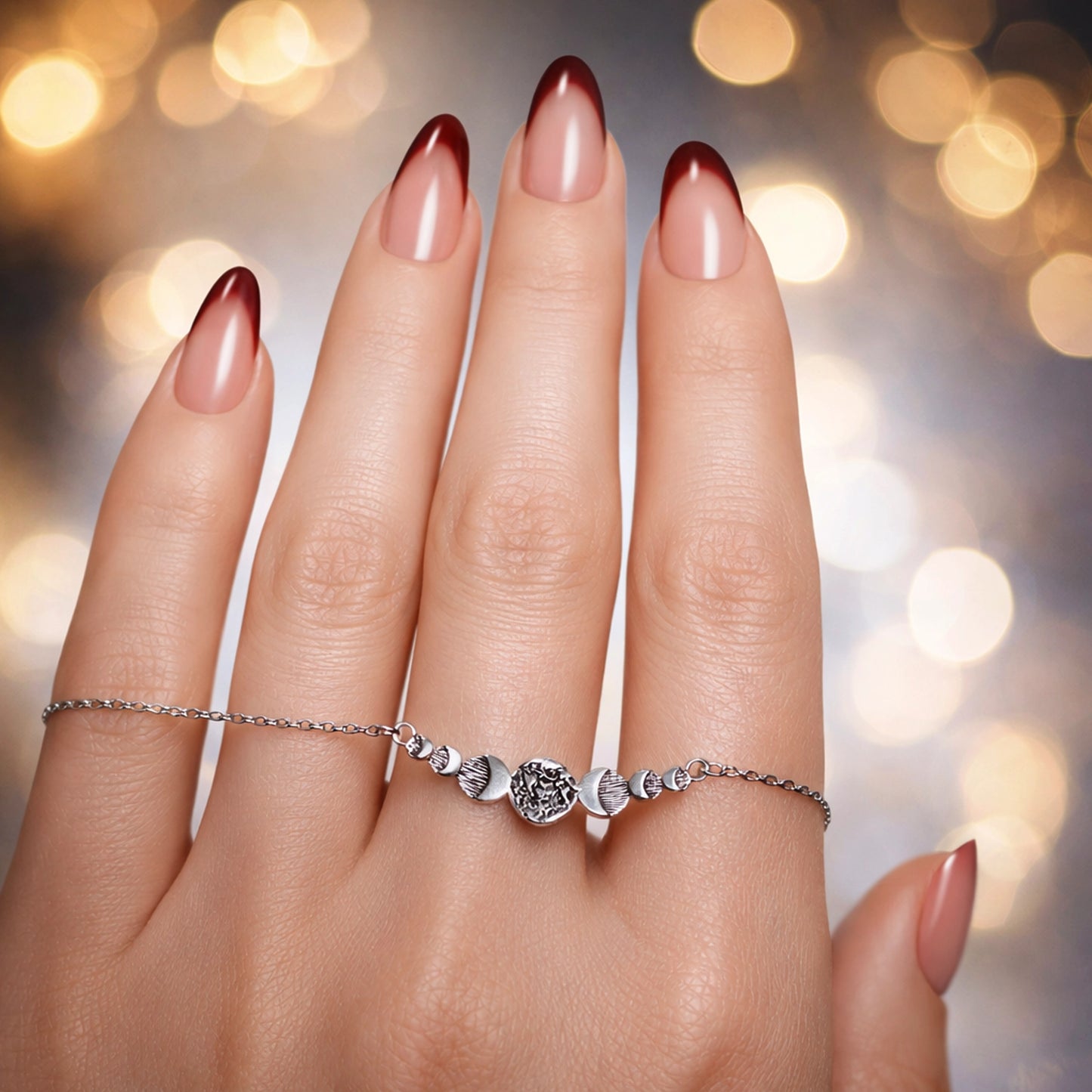 Close-up square photo of a woman’s hand with smooth skin and a glossy French manicure, wearing a delicate silver chain hand bracelet with small textured beads; jewelry is sharp and detailed, with soft professional studio lighting and an elegant blurred background.