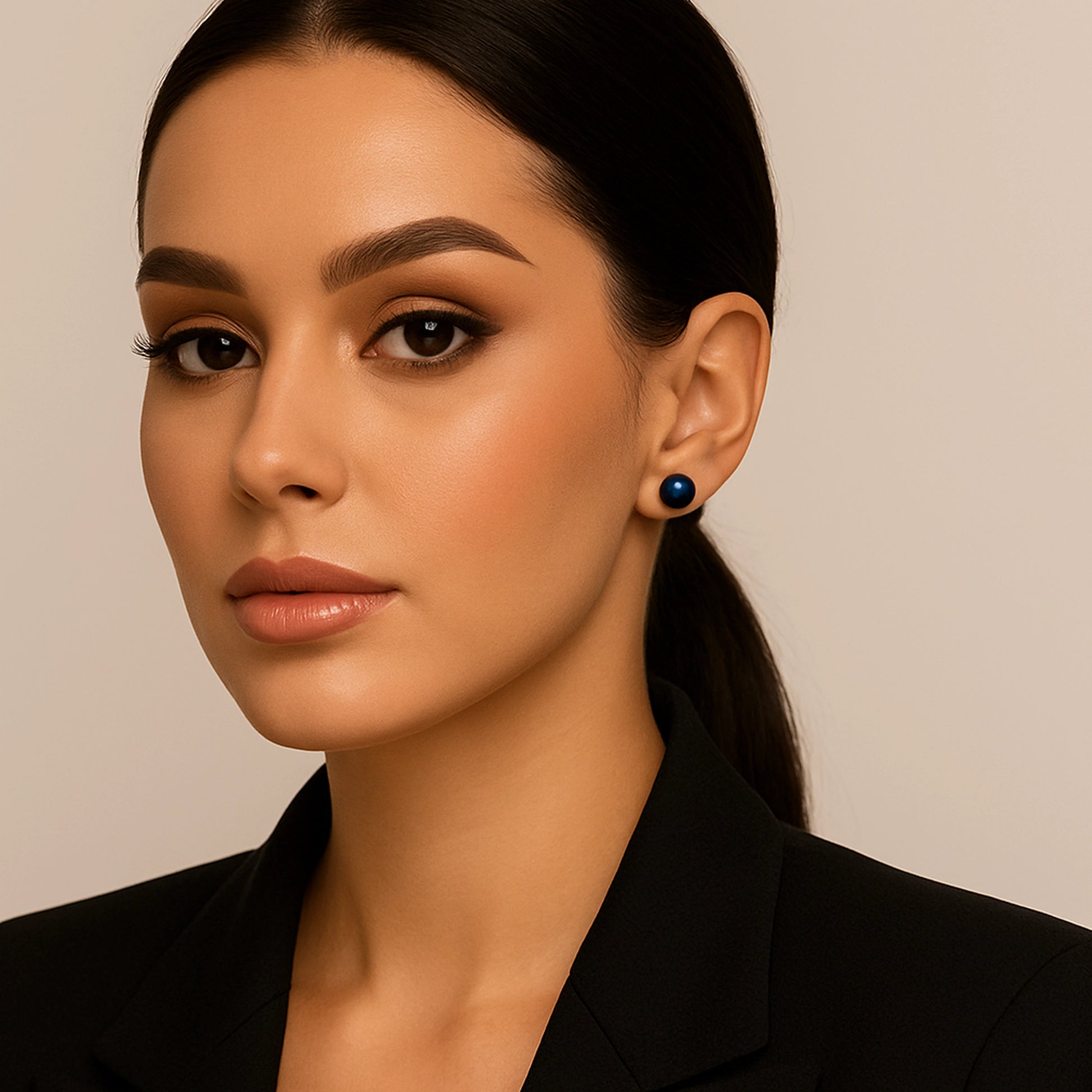 Elegant woman with sleek black hair and a black blazer wearing navy blue freshwater pearl stud earrings, showcasing a sophisticated and timeless look.