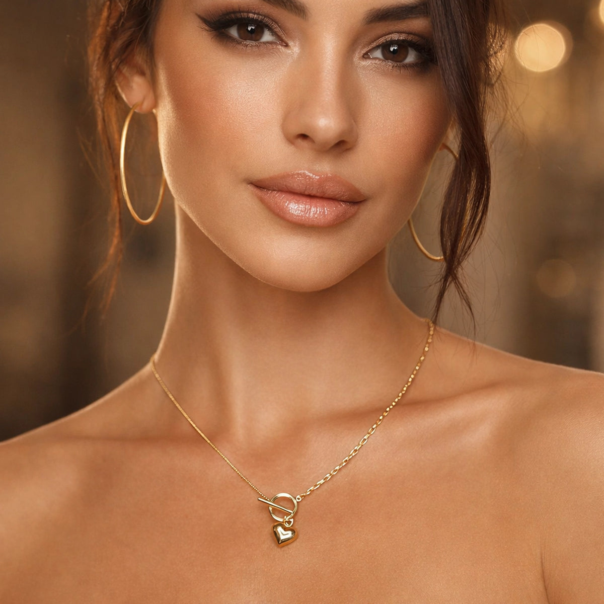 Woman wearing a gold necklace with a heart pendant against a warm-toned background