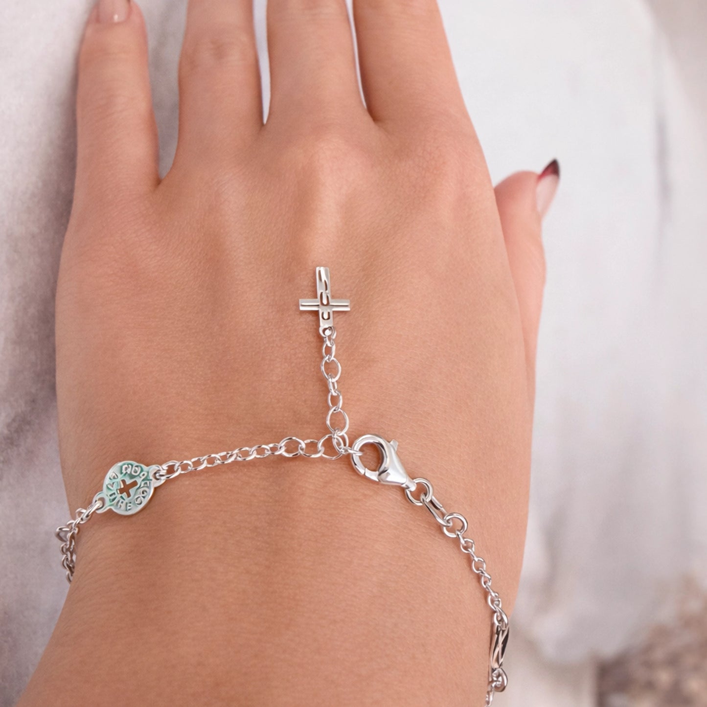 Sterling silver Catholic Padre Nostro bracelet on hand with adjustable chain, lobster clasp, turquoise enamel medal, and dangling cross charm