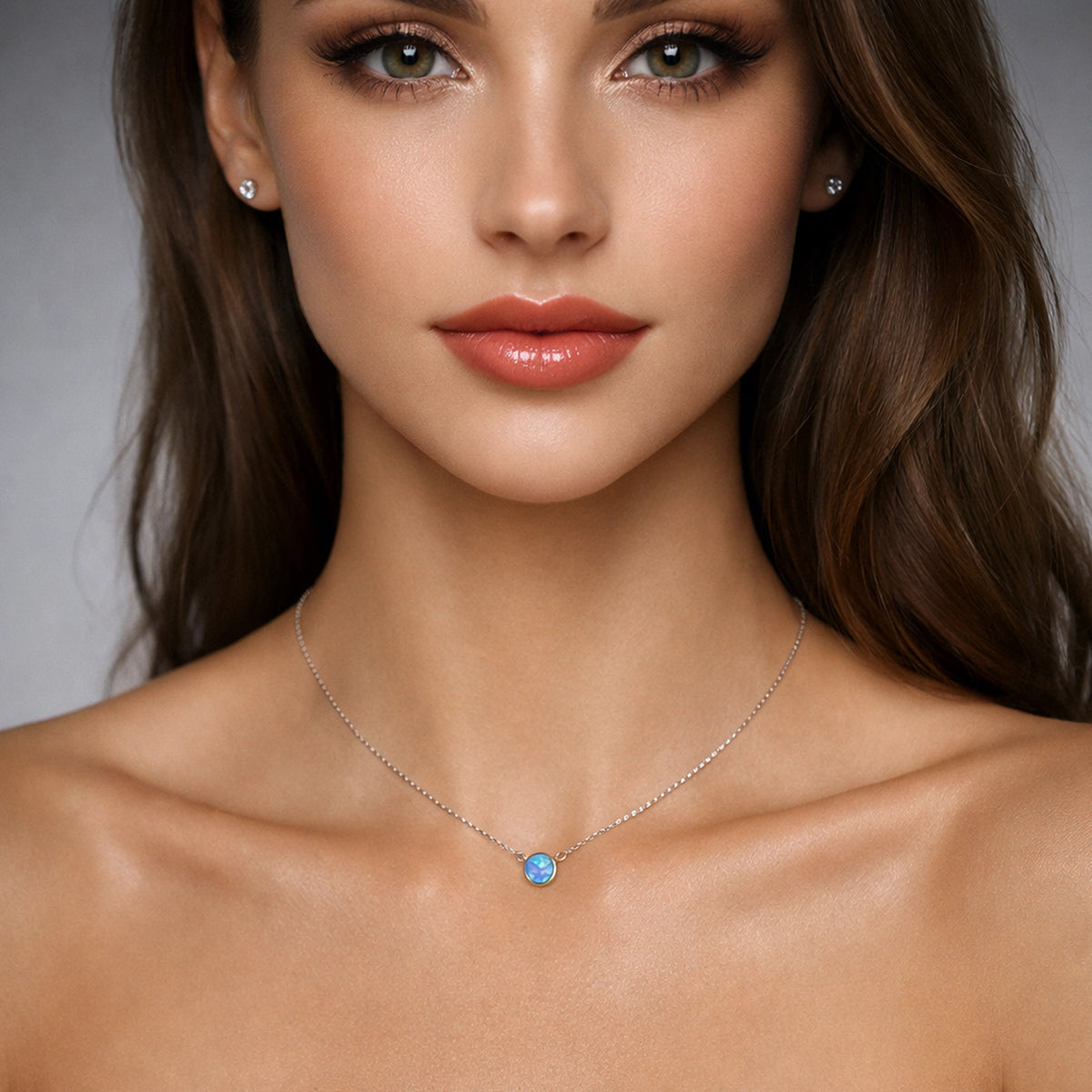 Close-up of a woman wearing a necklace with a blue gemstone against a neutral background