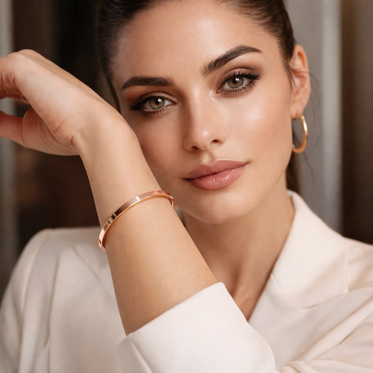 Beautiful woman wearing a delicate minimalist solid copper cuff bracelet on her wrist. Close-up portrait with soft professional lighting, natural glowing skin, neutral makeup, and a modern elegant white outfit. Simple timeless copper jewelry for everyday wear.