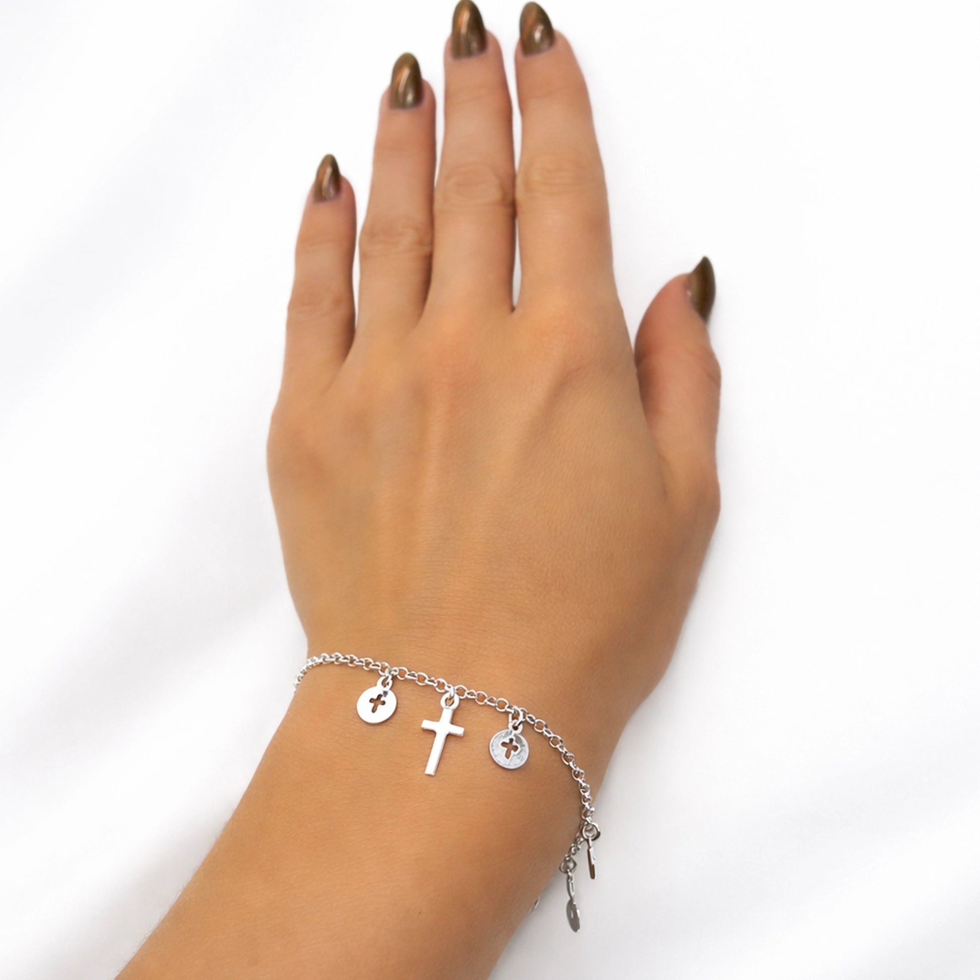 Elegant sterling silver rosary bracelet with delicate cross charms displayed on a woman's hand, featuring minimalist discs and a tiny cross pendant for a dainty religious-inspired look