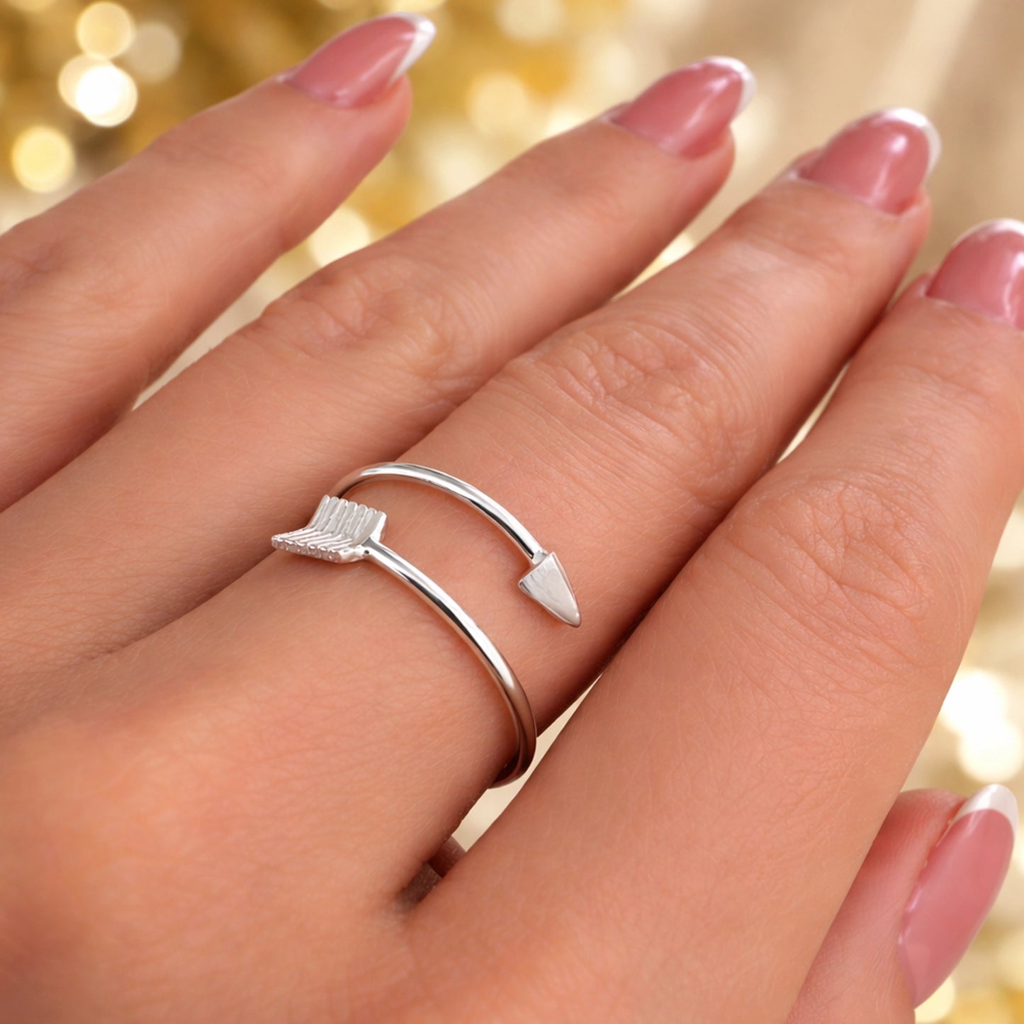 Close-up side view of a sterling silver arrow ring featuring a pointed tip and feathered fletching design, elegantly wrapping around the finger.