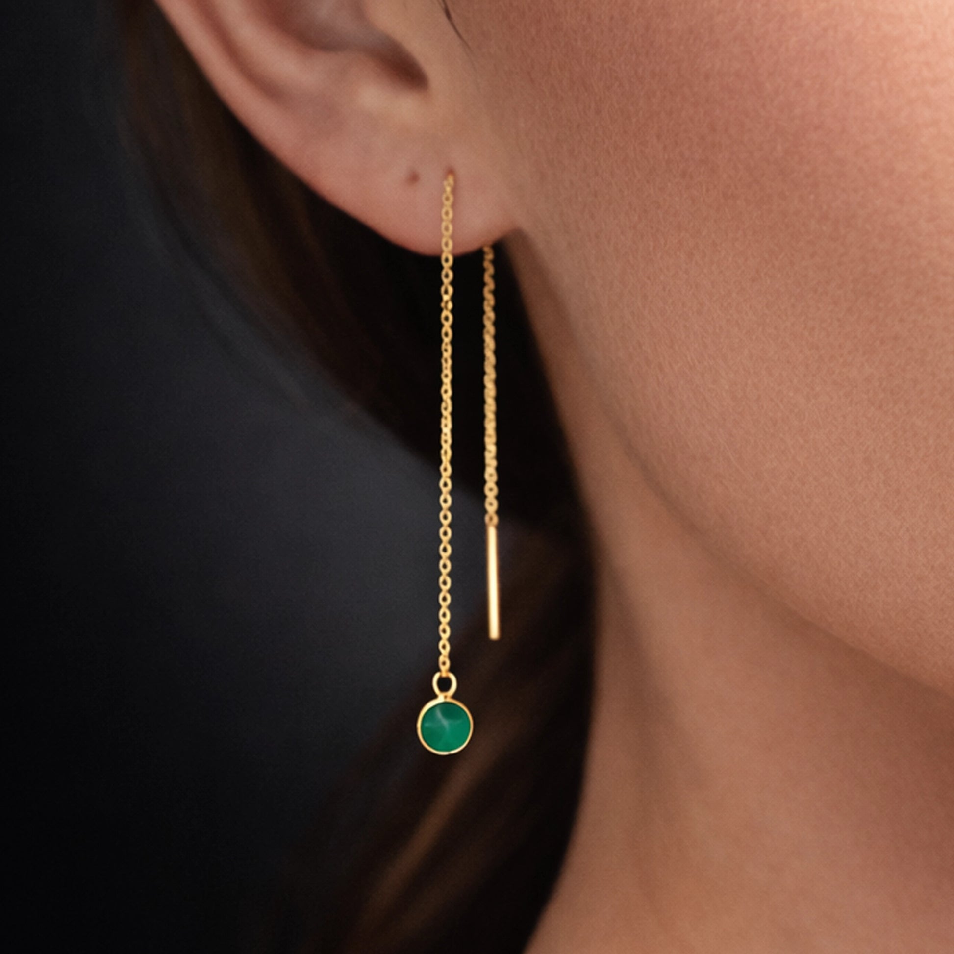 Gold threader drop earring with green onyx charm, close-up studio portrait on a model’s ear, sharp focus on delicate double chain and vertical bar detai