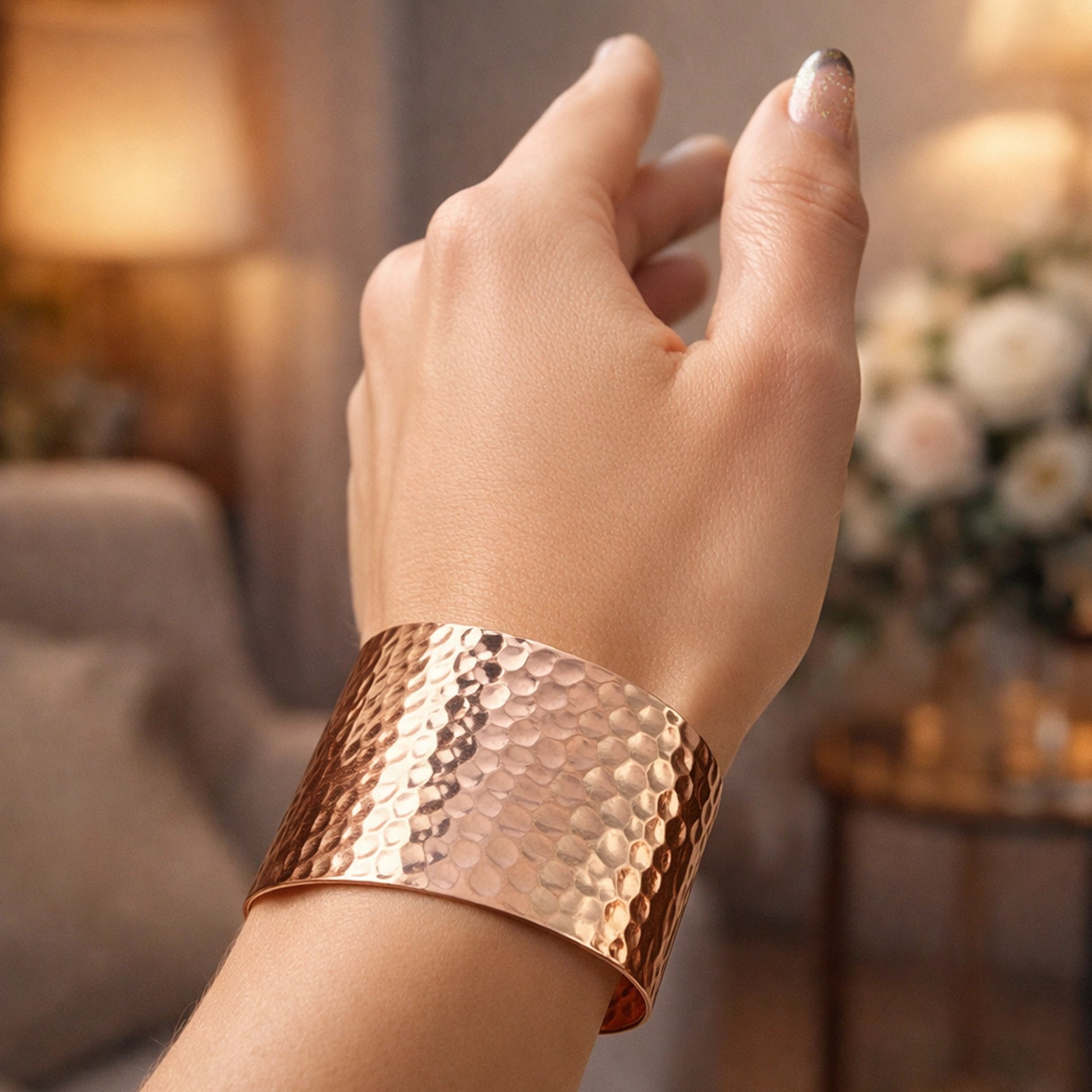 Hand wearing wide hammered copper cuff bracelet with warm polished texture, minimalist statement jewelry