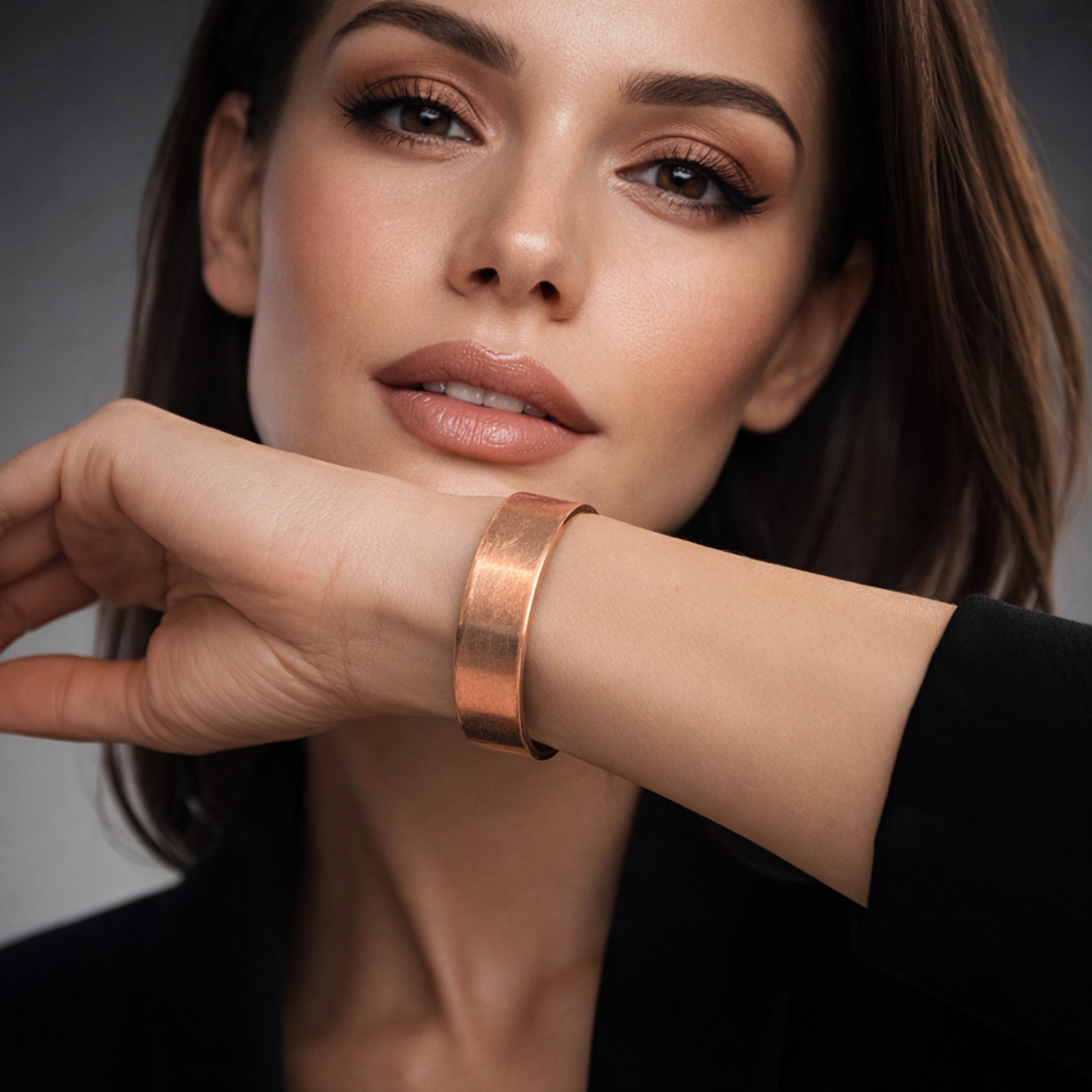 stylish, beautiful woman wearing a wide hammered copper cuff bracelet on her wrist. Soft, high-end lighting and a clean elegant background highlight the bracelet’s warm copper tone. No other jewelry is worn, keeping full focus on the copper cuff.