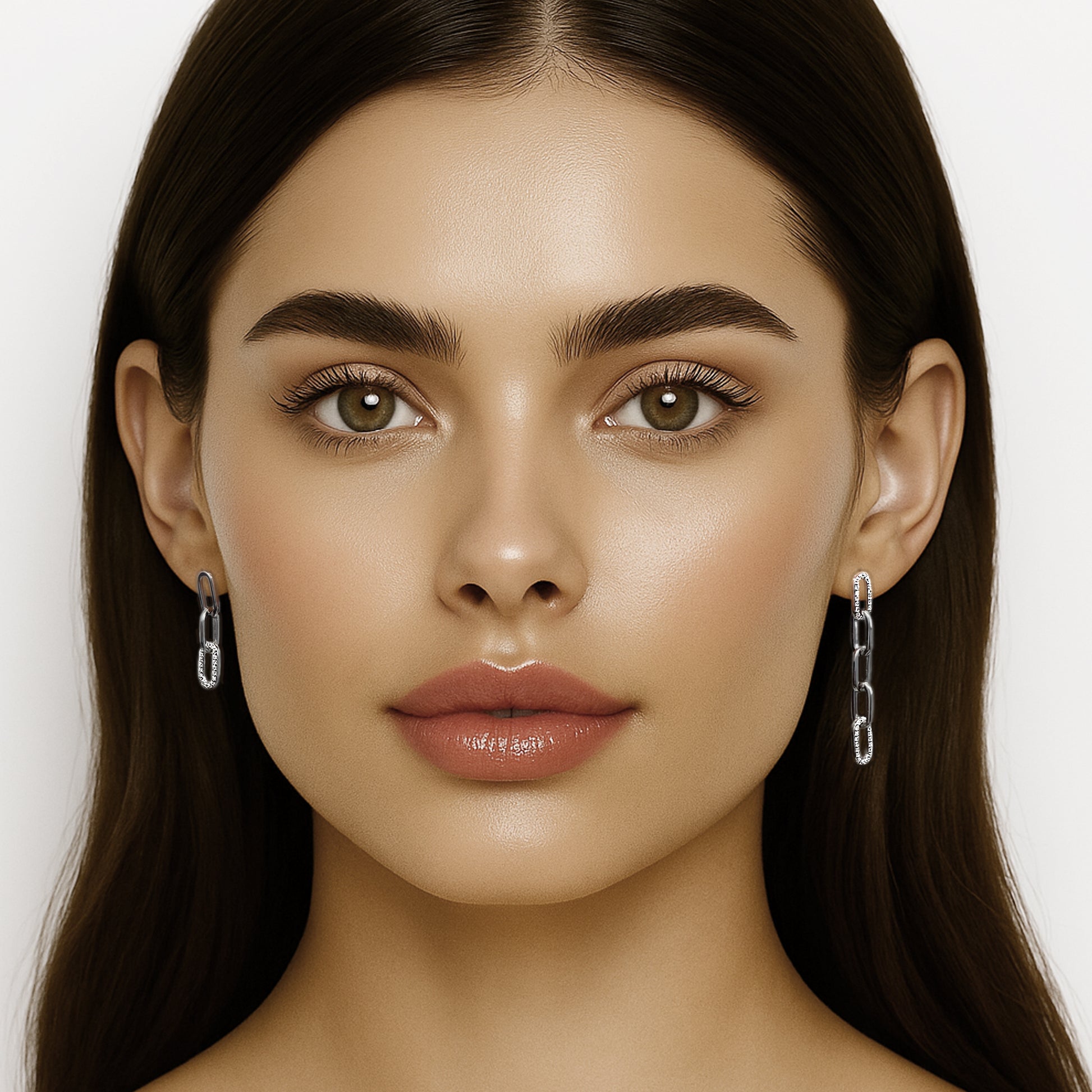 Frontal close-up of a brunette model with glowing makeup and glossy lips, wearing mismatched sterling silver CZ chain link drop earrings. Both ears are fully visible, with the right side featuring a long multi-link dangle and the left side showing a shorter version. Clean white background.