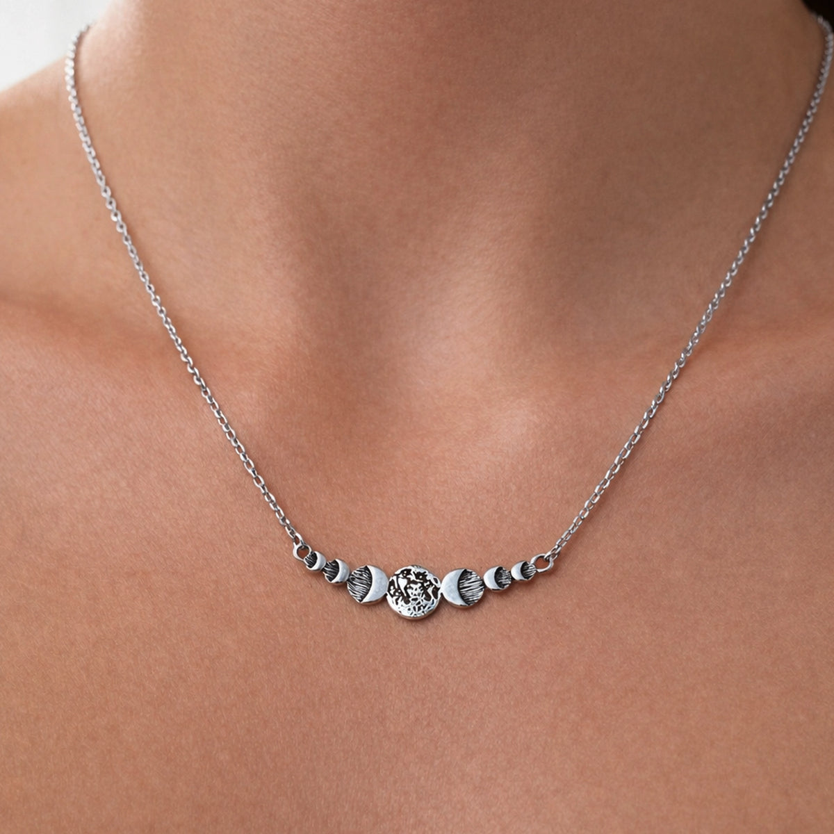 delicate silver moon-phase necklace with a central textured lunar bar, natural skin texture, soft professional lighting.