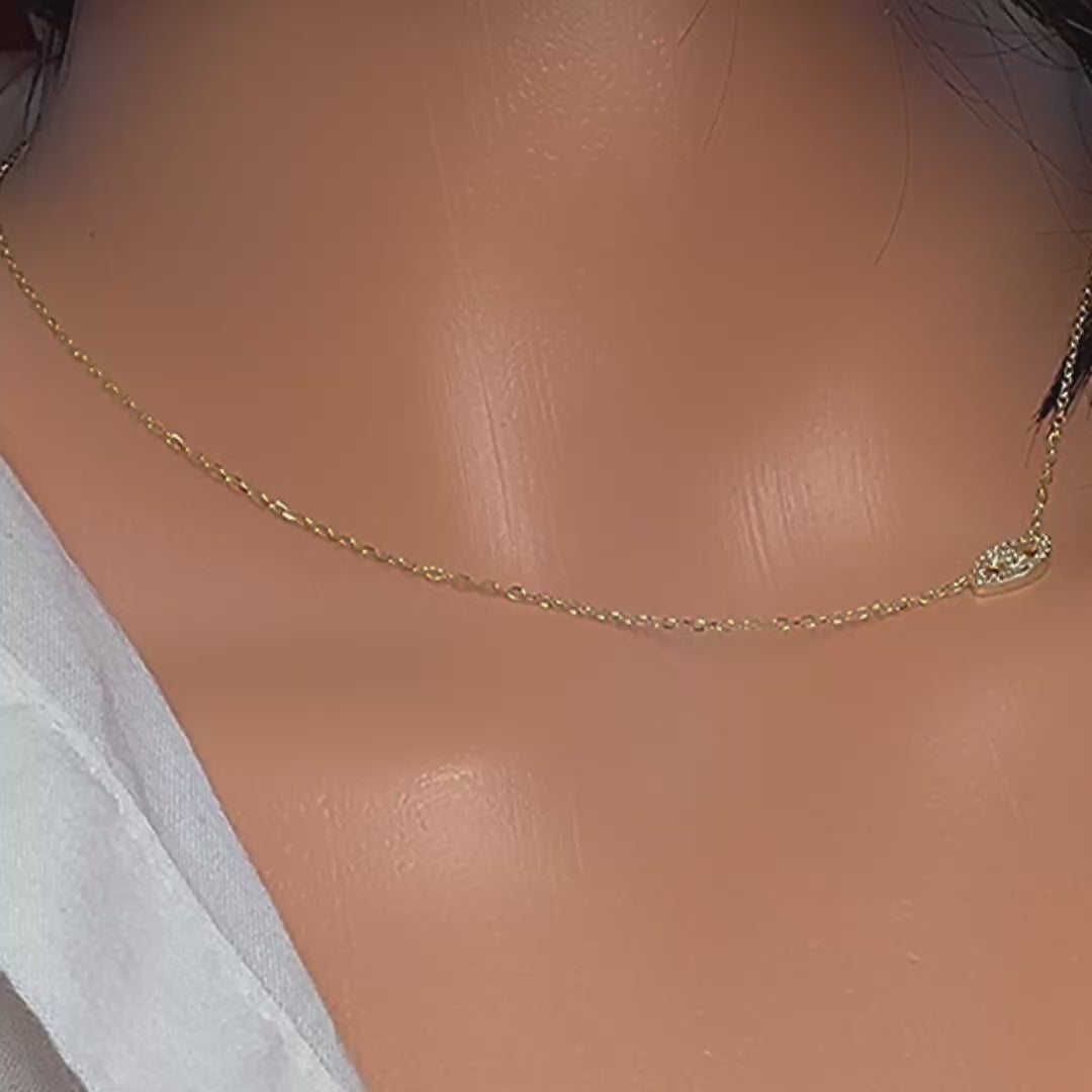 Video of a dainty CZ evil eye charm necklace in gold, shown close-up with a delicate gold chain and sparkling eye-shaped pendant, capturing the shimmer and fine details as it moves.