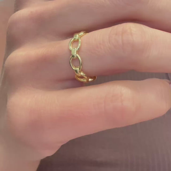 Video showcasing a trendy gold chain link ring worn on the hand, highlighting its open adjustable band and polished finish. The camera slowly moves to capture the reflective shine and interlocking links from multiple angles.