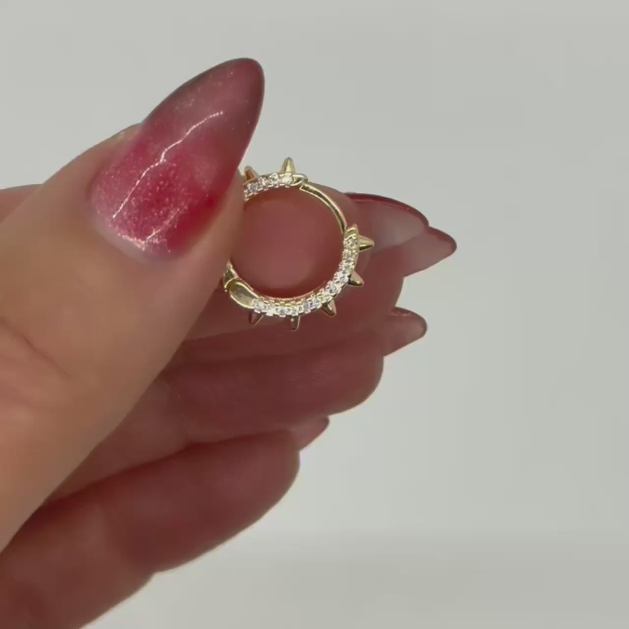 Rotating close-up video of 18k gold filled spike hoop earrings with cubic zirconia detail, showing the circular shape, pointed edges, and sparkling CZ stones against a white background.