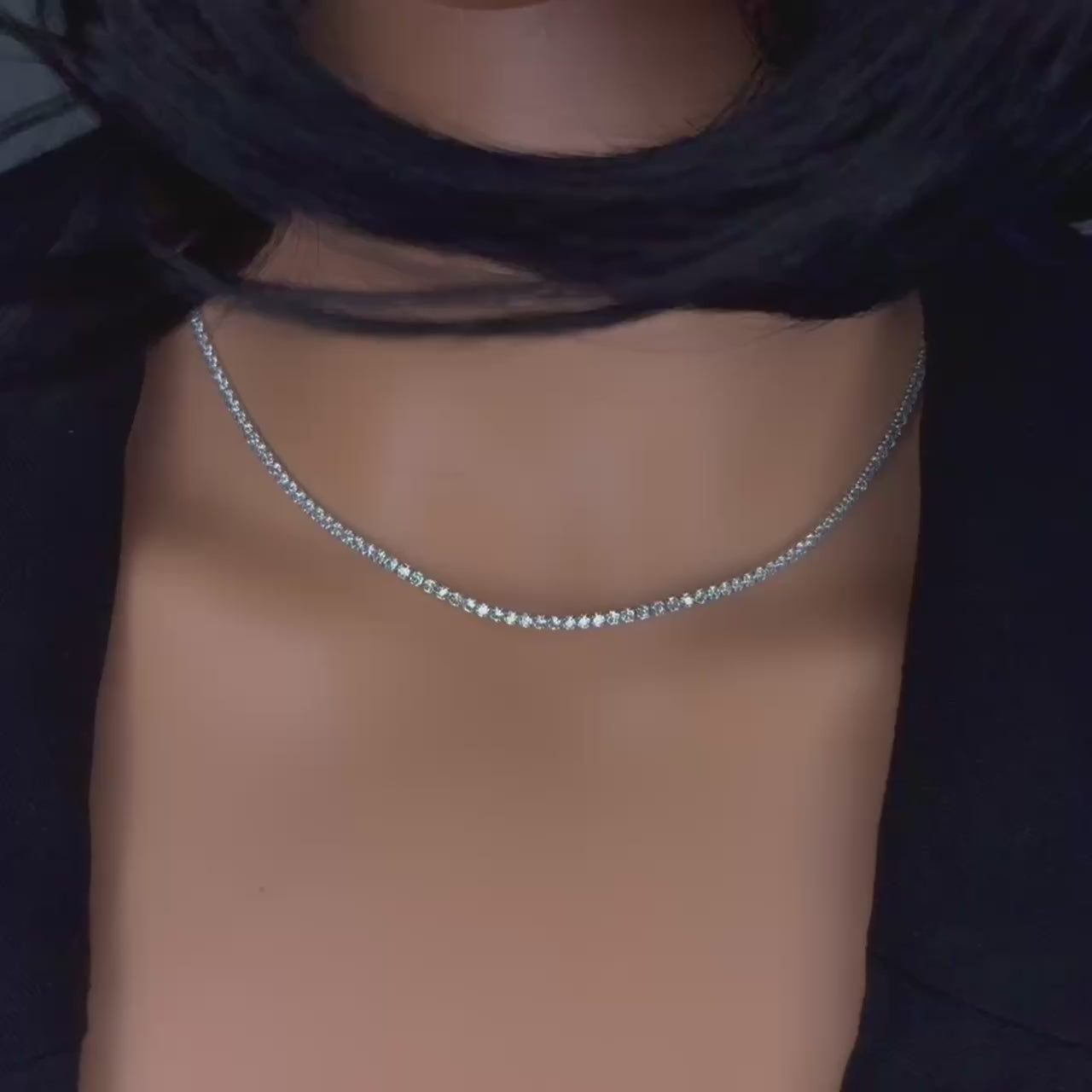 Video showcasing a sterling silver tennis chain necklace worn by a model. The necklace features a continuous row of dazzling cubic zirconia stones that catch the light with movement, creating a bright, diamond-like sparkle along the collarbone.