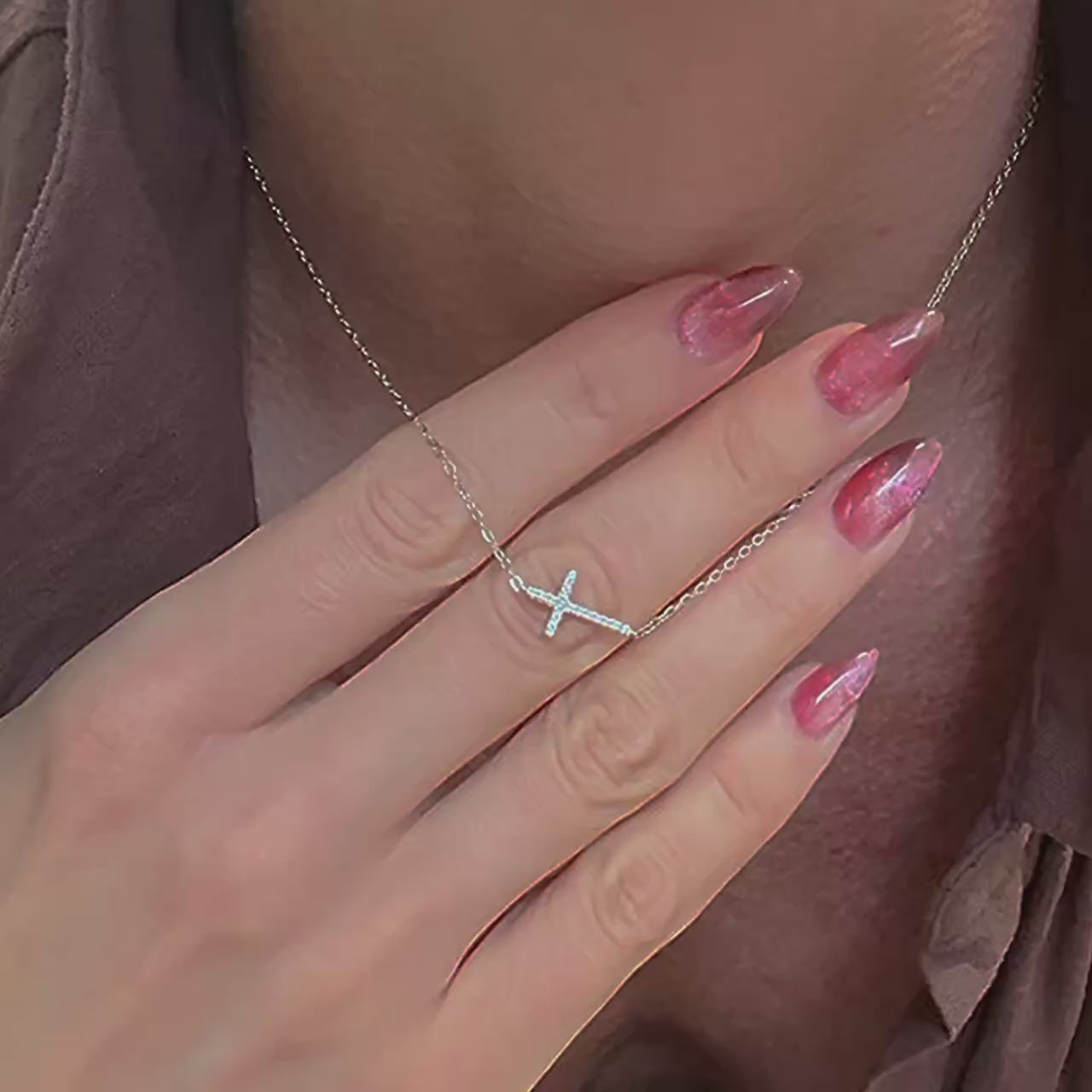 A dainty sterling silver necklace featuring a sideways CZ cross pendant, gently resting on the mannequin’s neckline. The camera pans to show the fine chain and sparkling cubic zirconia details, styled with a soft white shirt.