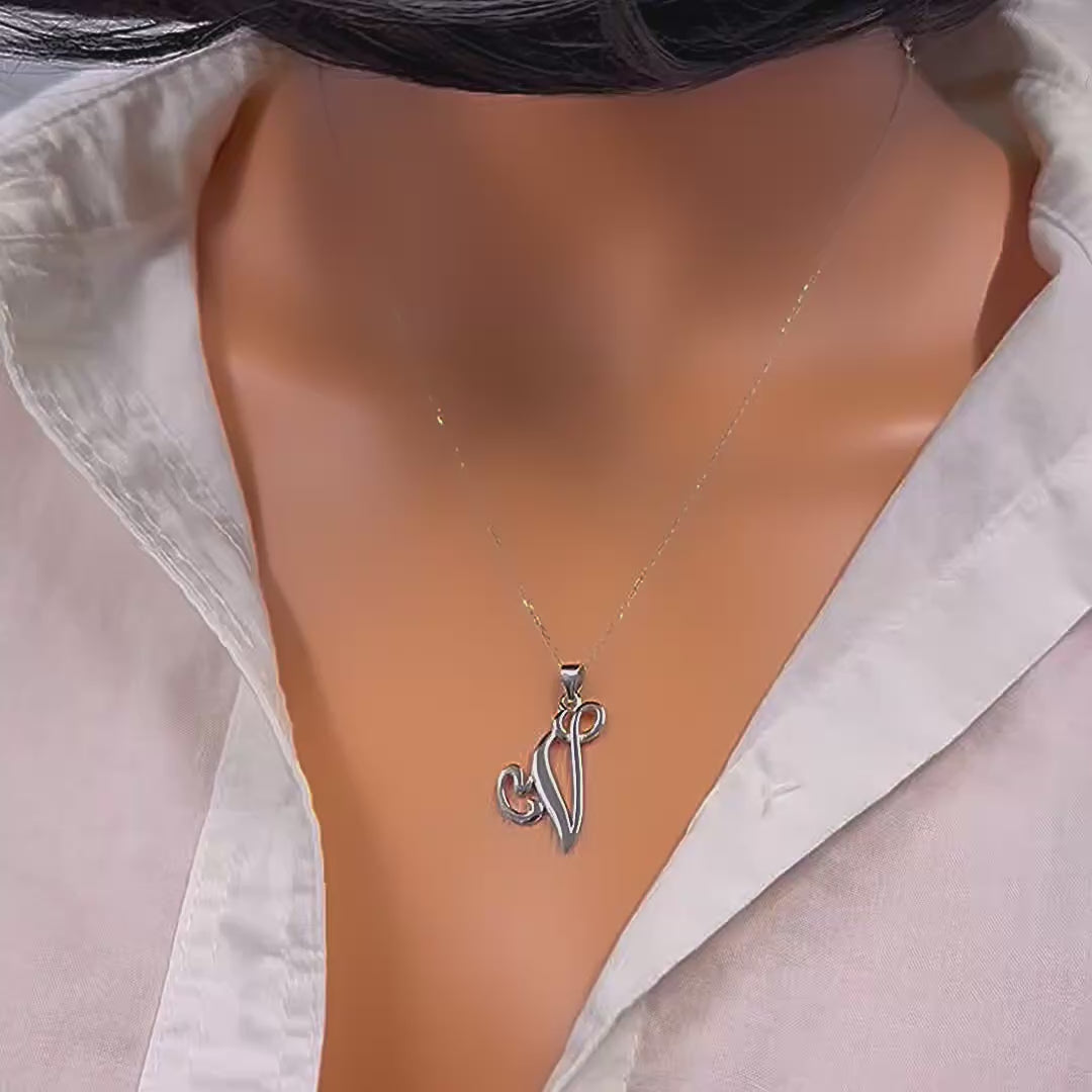 Video of a large sterling silver initial letter pendant necklace hanging from a delicate chain, displayed on a model wearing an open white shirt.