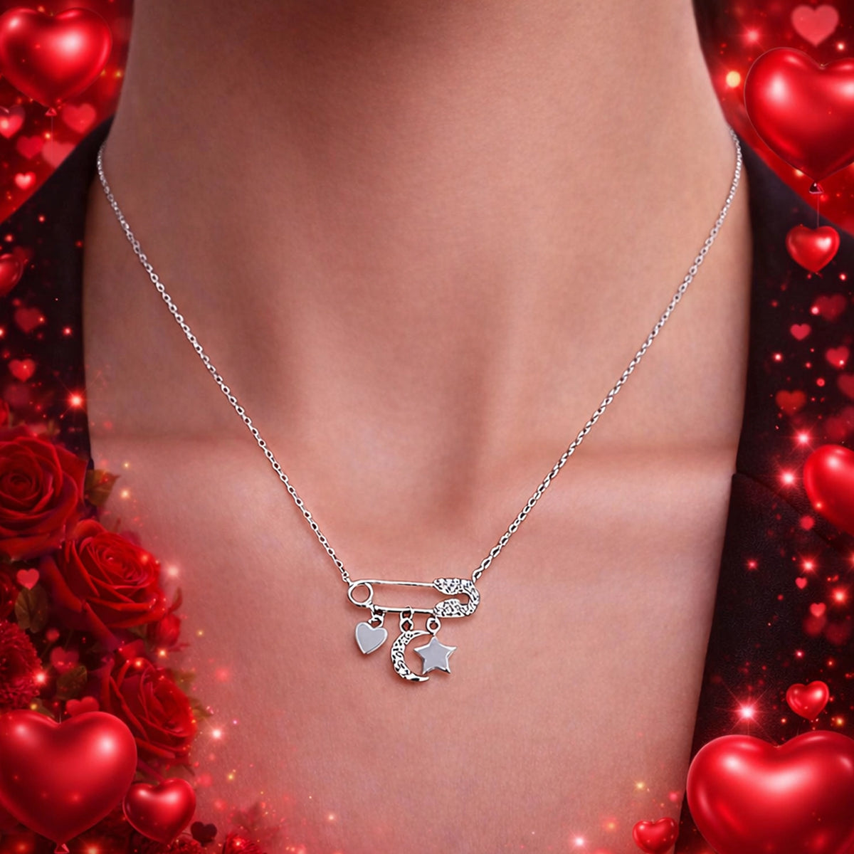 Close-up of a silver safety pin necklace with heart, crescent moon, and star charms on a woman’s neckline, styled for a Valentine’s Day jewelry promotion with a soft red heart background.