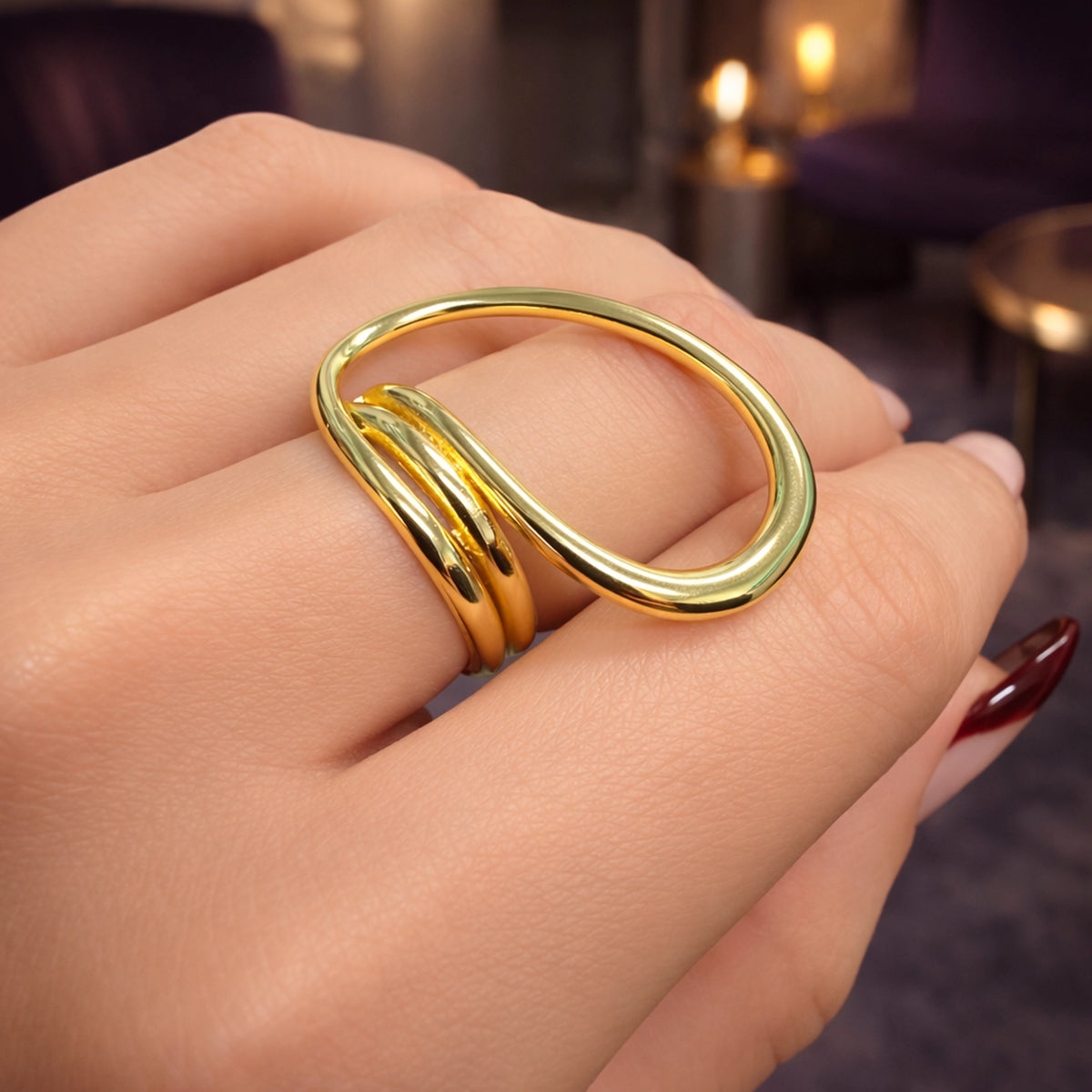 Close-up of a woman’s hand wearing a modern abstract gold ring with a smooth sculptural design, polished gold statement ring on finger with elegant manicure, stylish minimalist jewelry accessory with contemporary curved shape.
