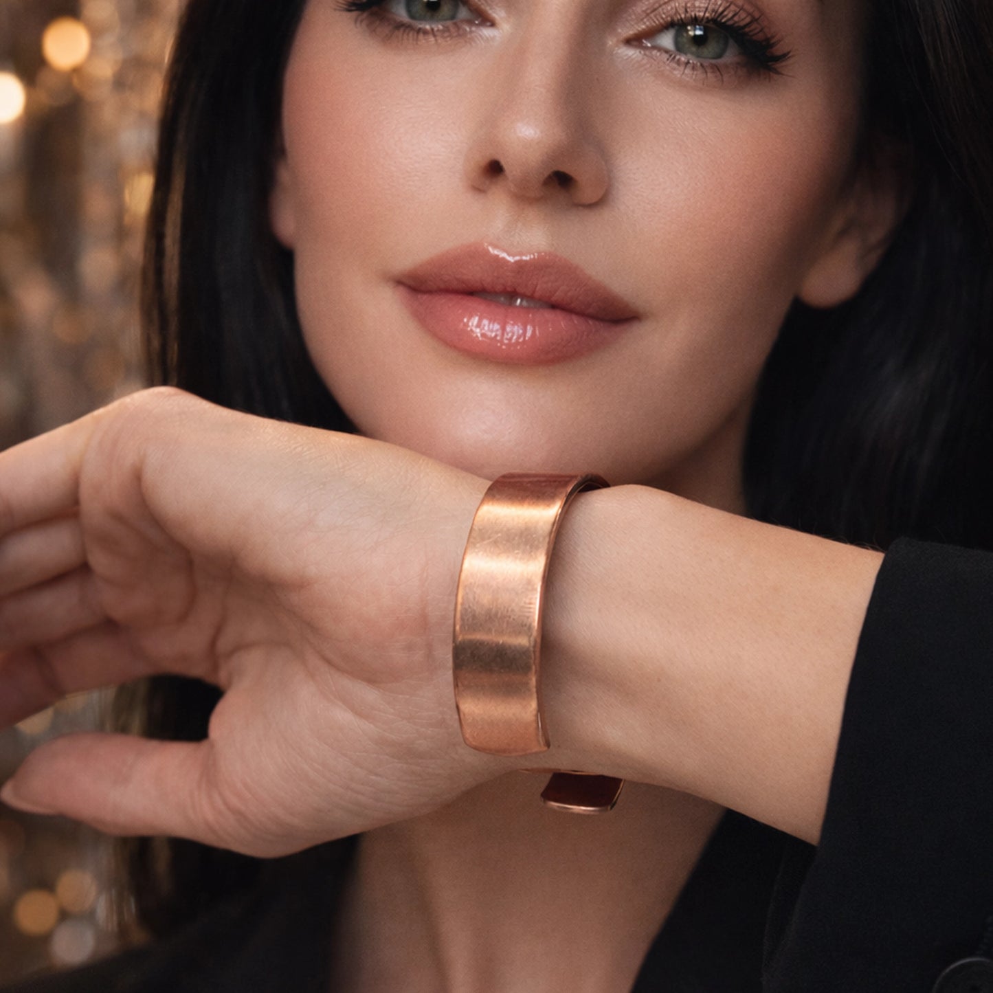Beautiful woman wearing a minimalist copper open cuff bracelet on her wrist, glossy lips and flawless skin, professional studio lighting with a warm blurred background, close-up jewelry focus, elegant modern style.