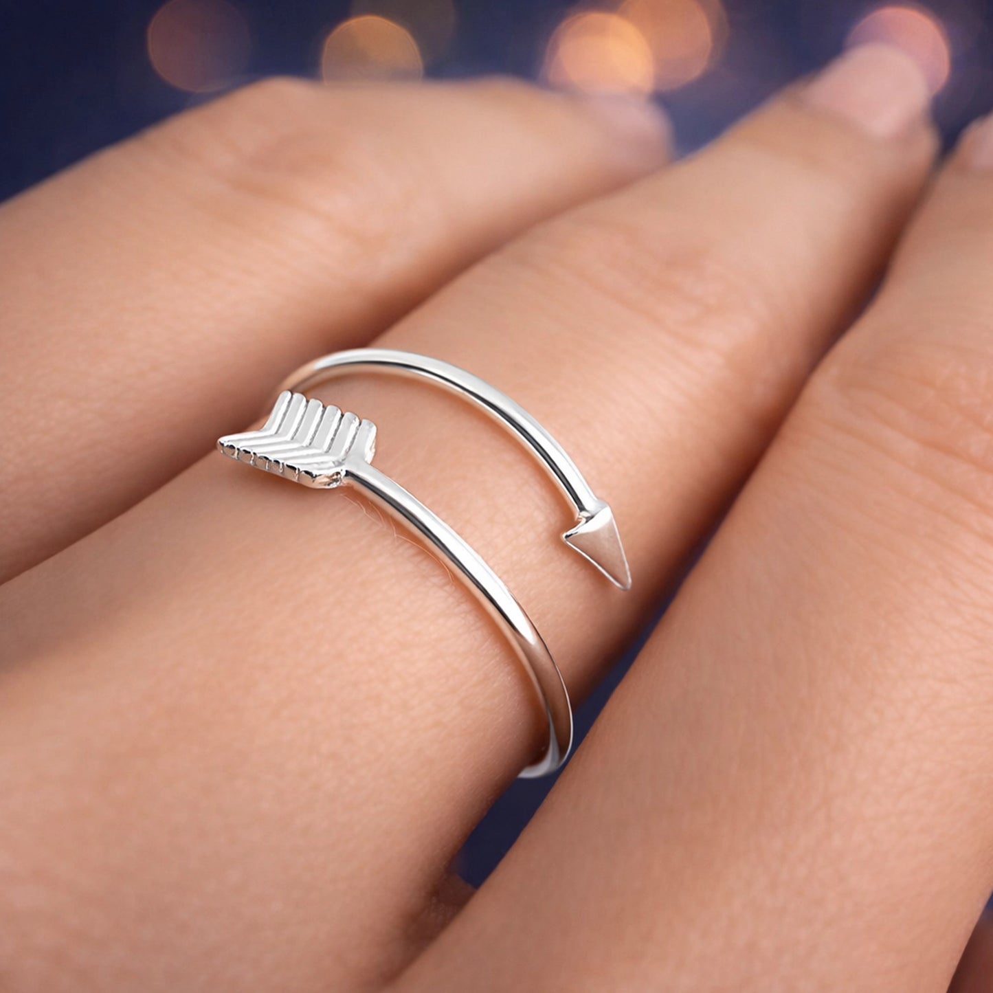 Close-up side view of a sterling silver arrow ring featuring a pointed tip and feathered fletching design, elegantly wrapping around the finger.