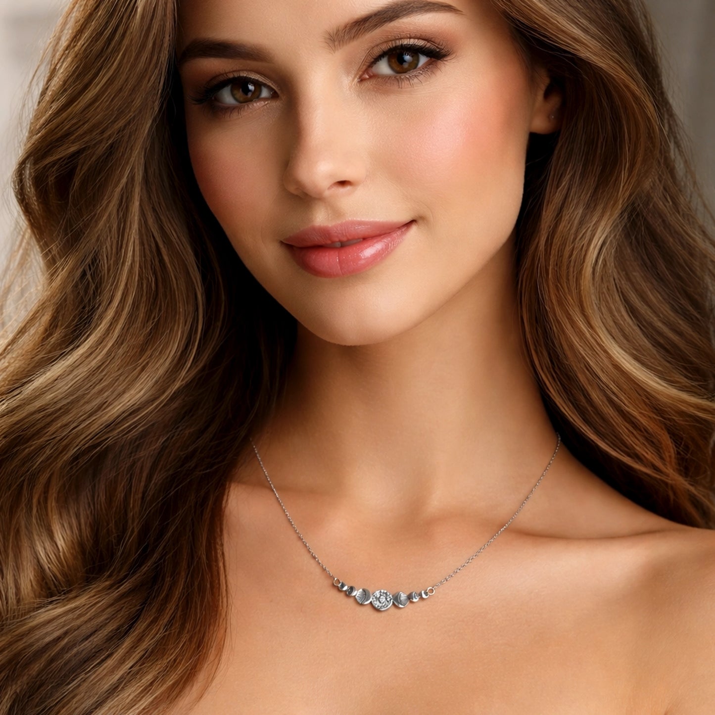 beautiful model wearing a delicate silver necklace with a small round textured center charm and symmetrical crescent details on a fine chain, shown at true-to-life scale on the neck, with professional soft lighting and a clean, elegant background highlighting the necklace