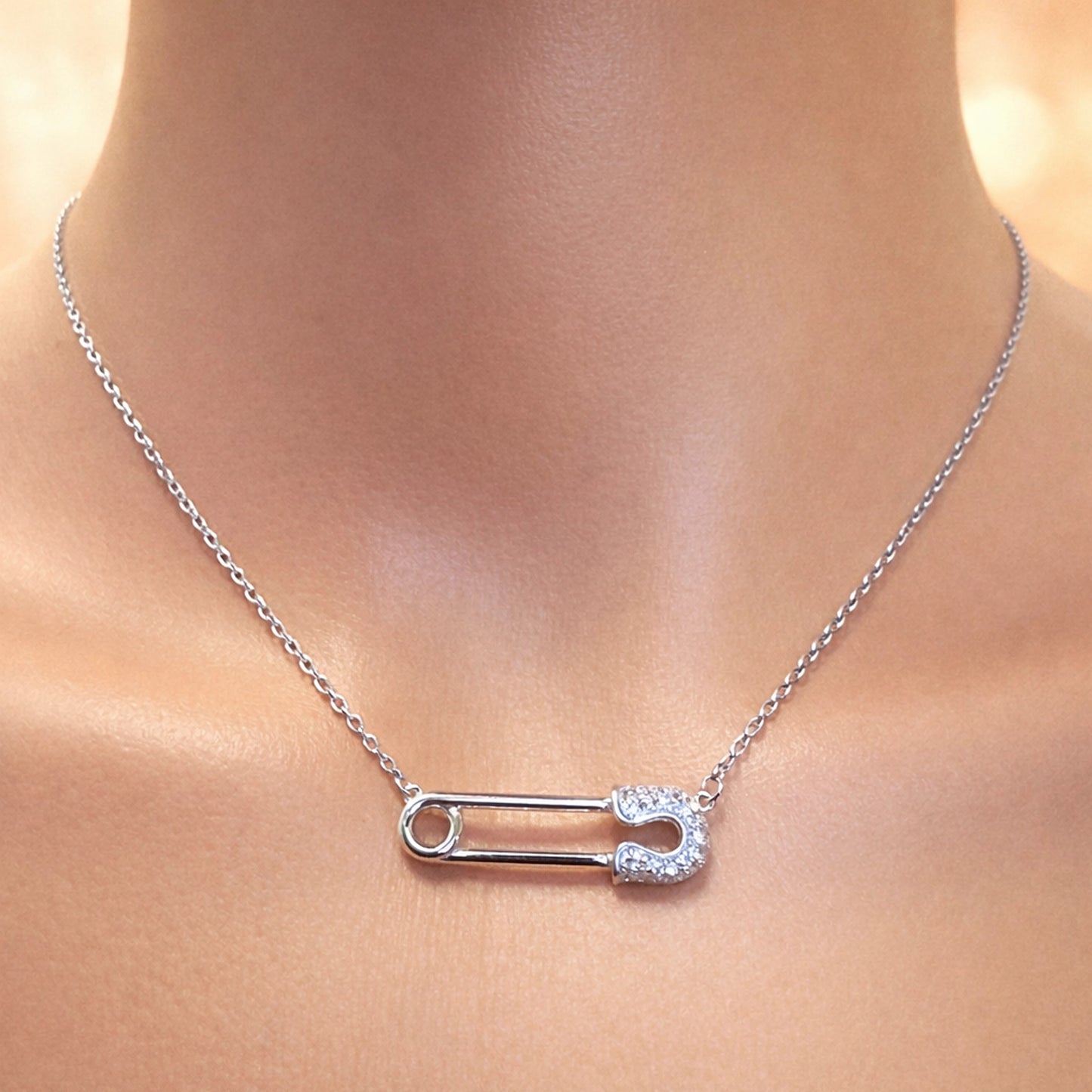 Silver Safety Pin Necklace with Rock Crystal Stones • Sterling Silver with Rhodium Plating • Minimalist Safety Pin Pendant on Delicate Chain • Modern Elegant Jewelry Close-Up on Model Neck • Sparkling Crystal Safety Pin Necklace