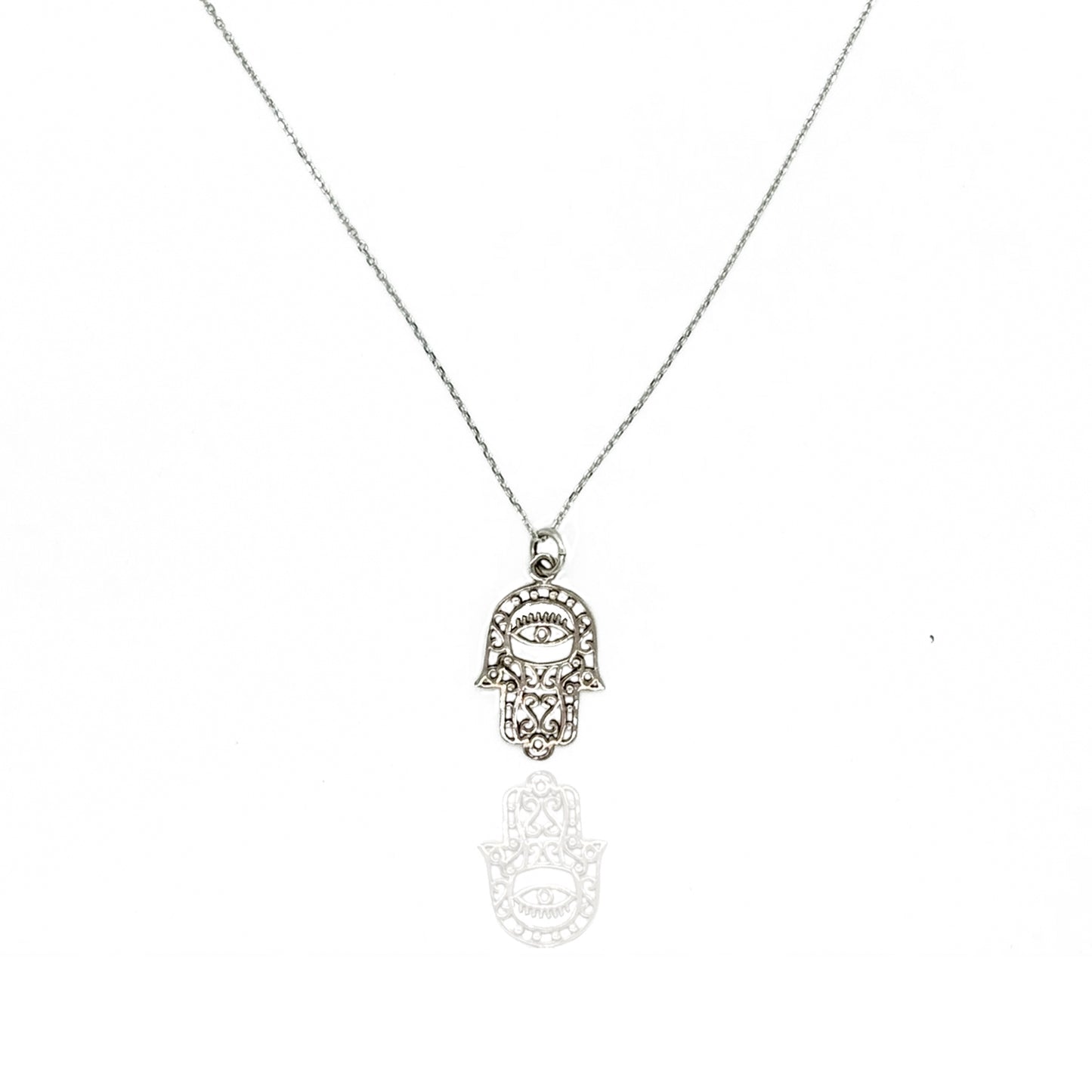 Sterling silver hamsa and evil eye necklace with intricate lace filigree hand-shaped pendant on a delicate fine chain, photographed on a white background with a subtle reflection below.