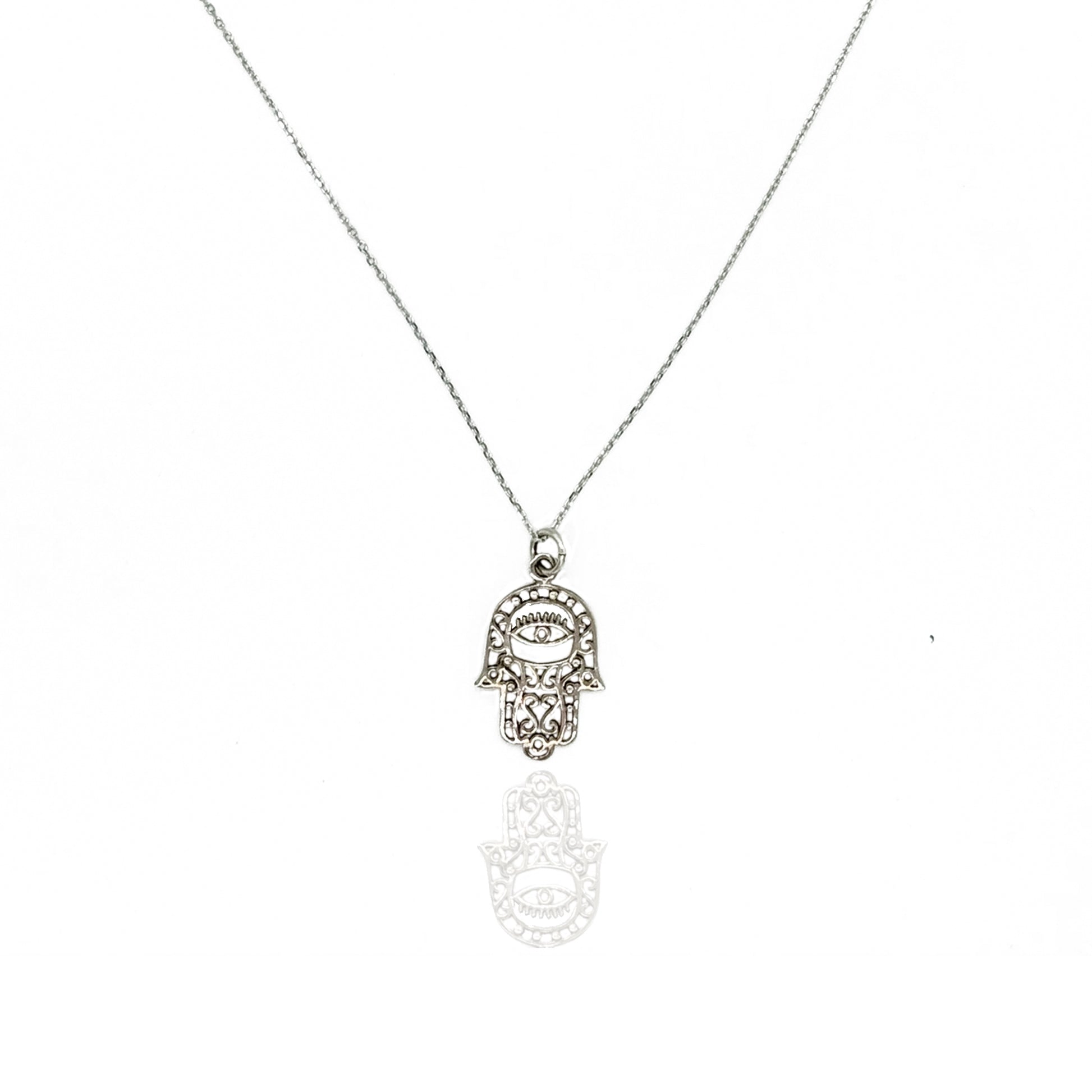 Sterling silver hamsa and evil eye necklace with intricate lace filigree hand-shaped pendant on a delicate fine chain, photographed on a white background with a subtle reflection below.