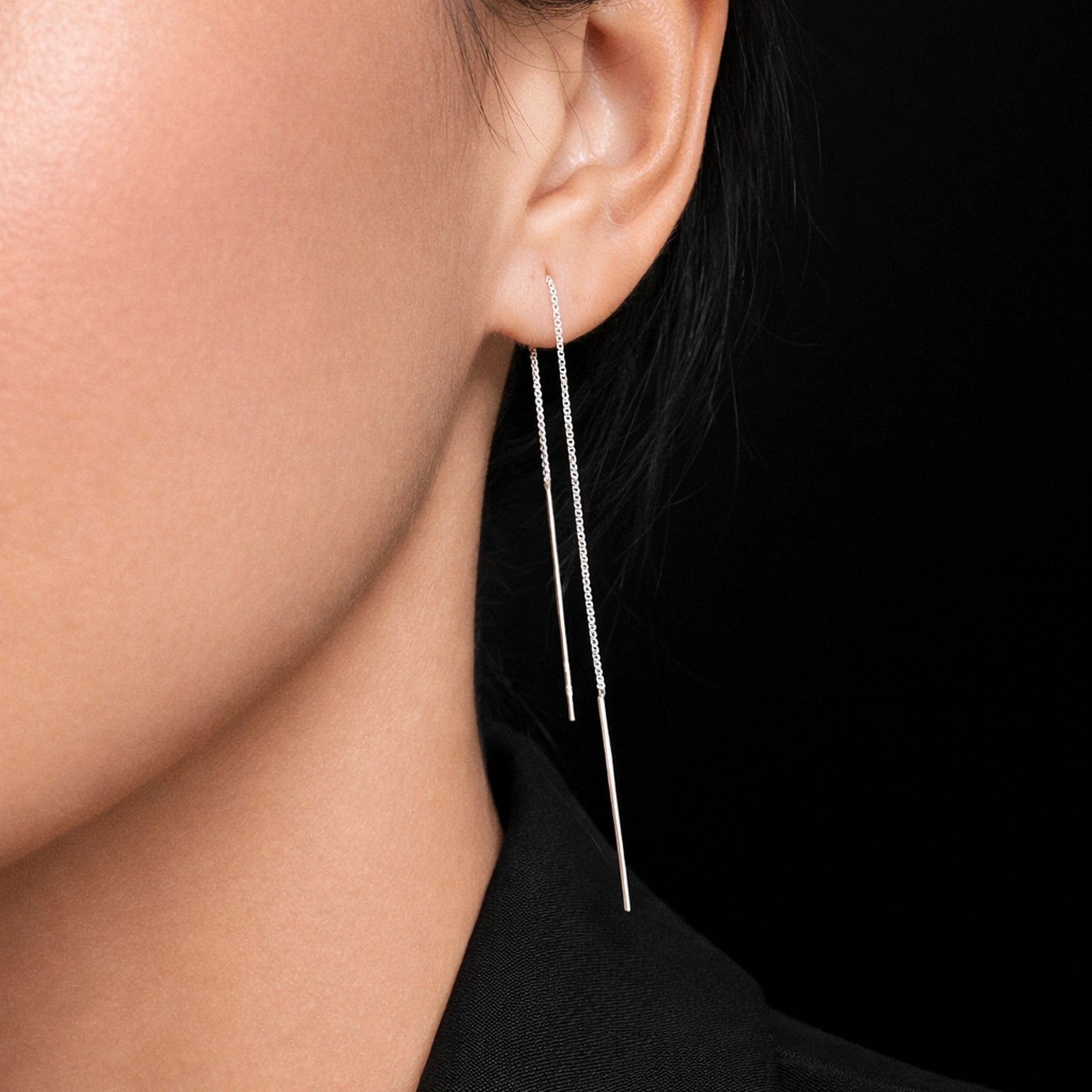 Silver threader drop earrings with box chain and long bar ends, shown in a close-up studio portrait on a model wearing a black blazer, featuring smooth flawless skin, professional lighting, high contrast, and sharp detailed focus on the minimalist dangle earring design.