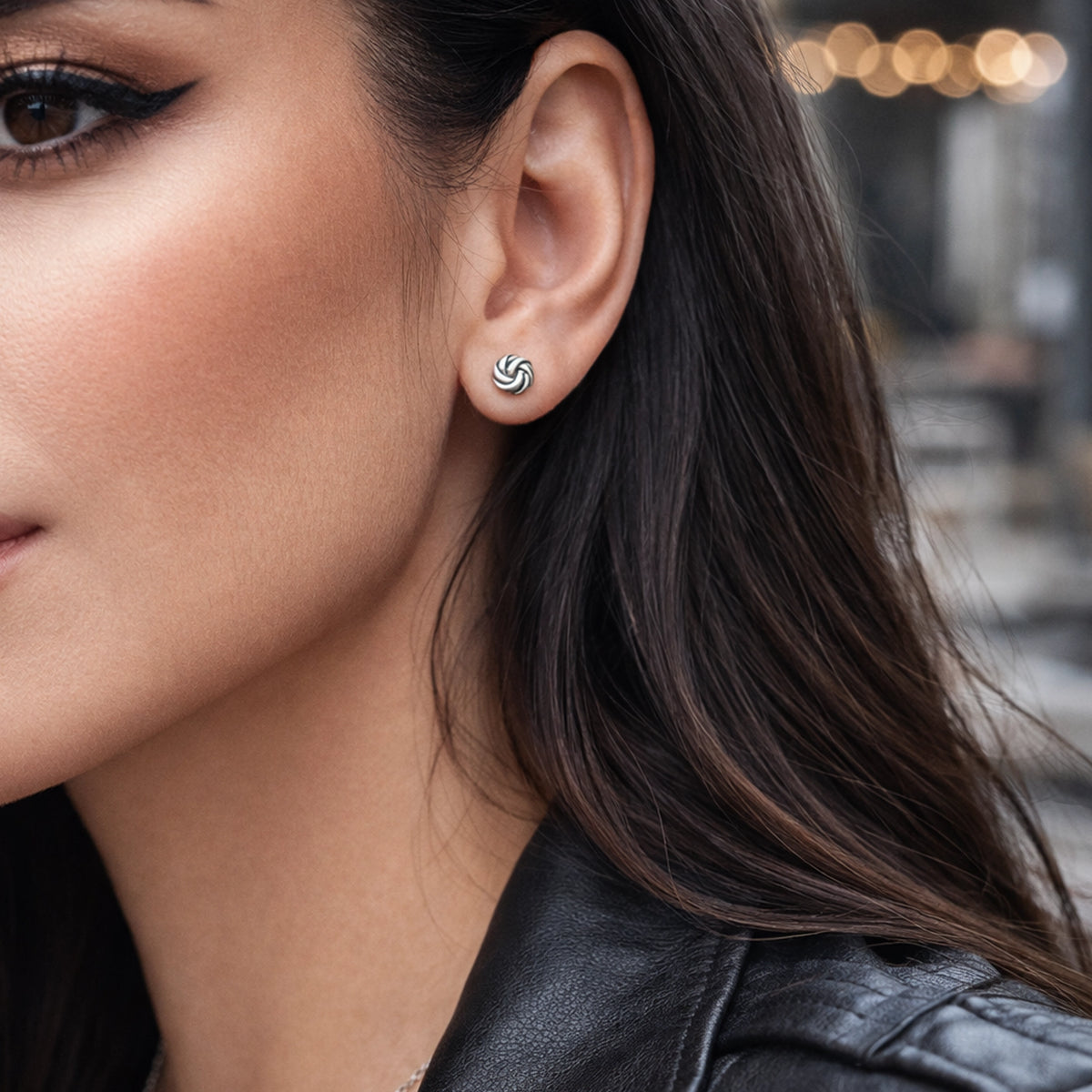 Sterling silver twisted knot stud earrings on model, minimalist swirl stud earrings, small spiral knot earrings, modern everyday silver stud jewelry, elegant simple studs for women.
