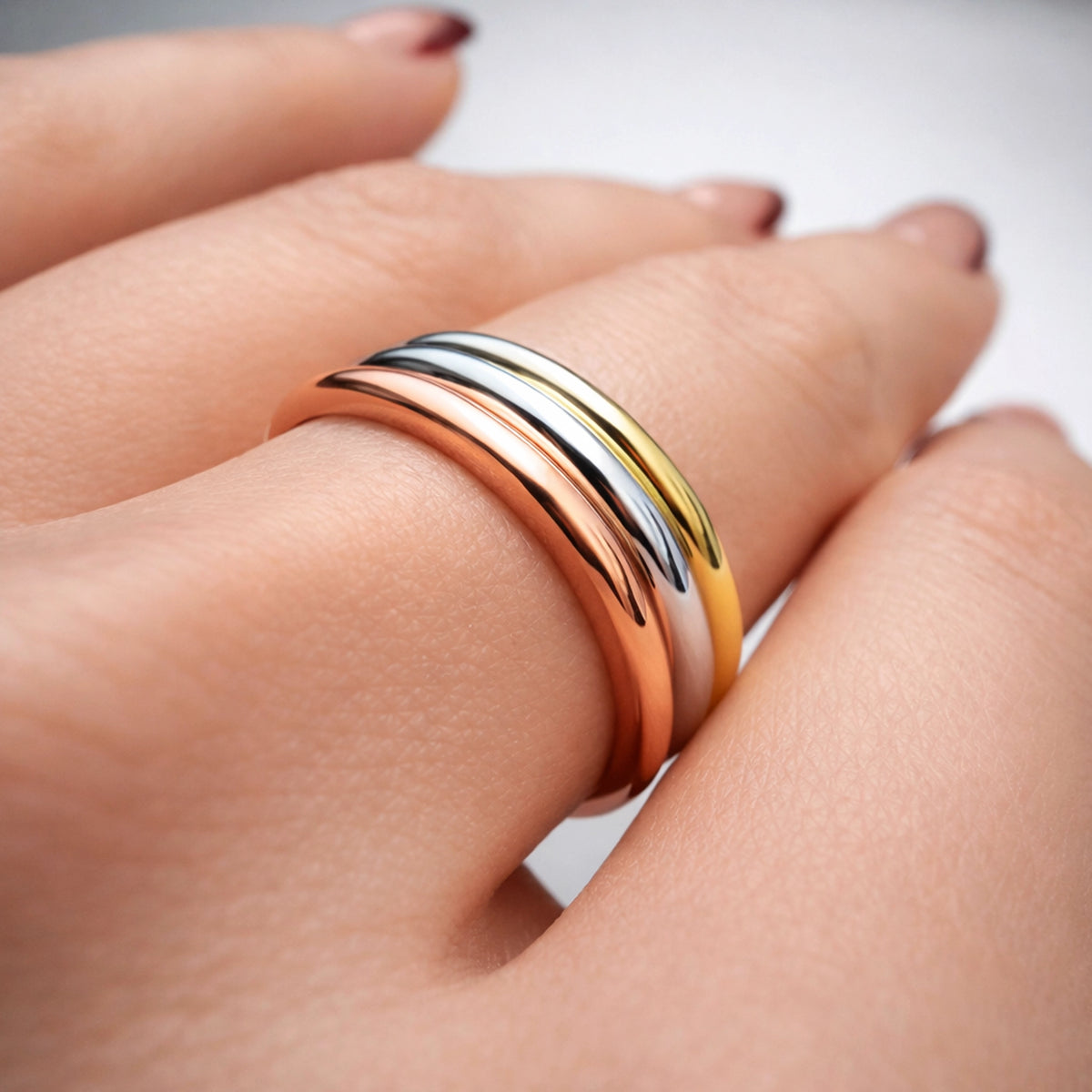 Tricolor stacking rings set in rose gold, yellow gold, and rhodium plated silver tones on finger, minimalist modern band rings, elegant everyday jewelry