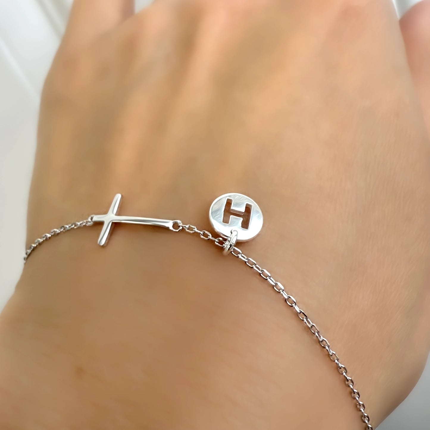 Silver bracelet with a letter 'H' charm on a wrist